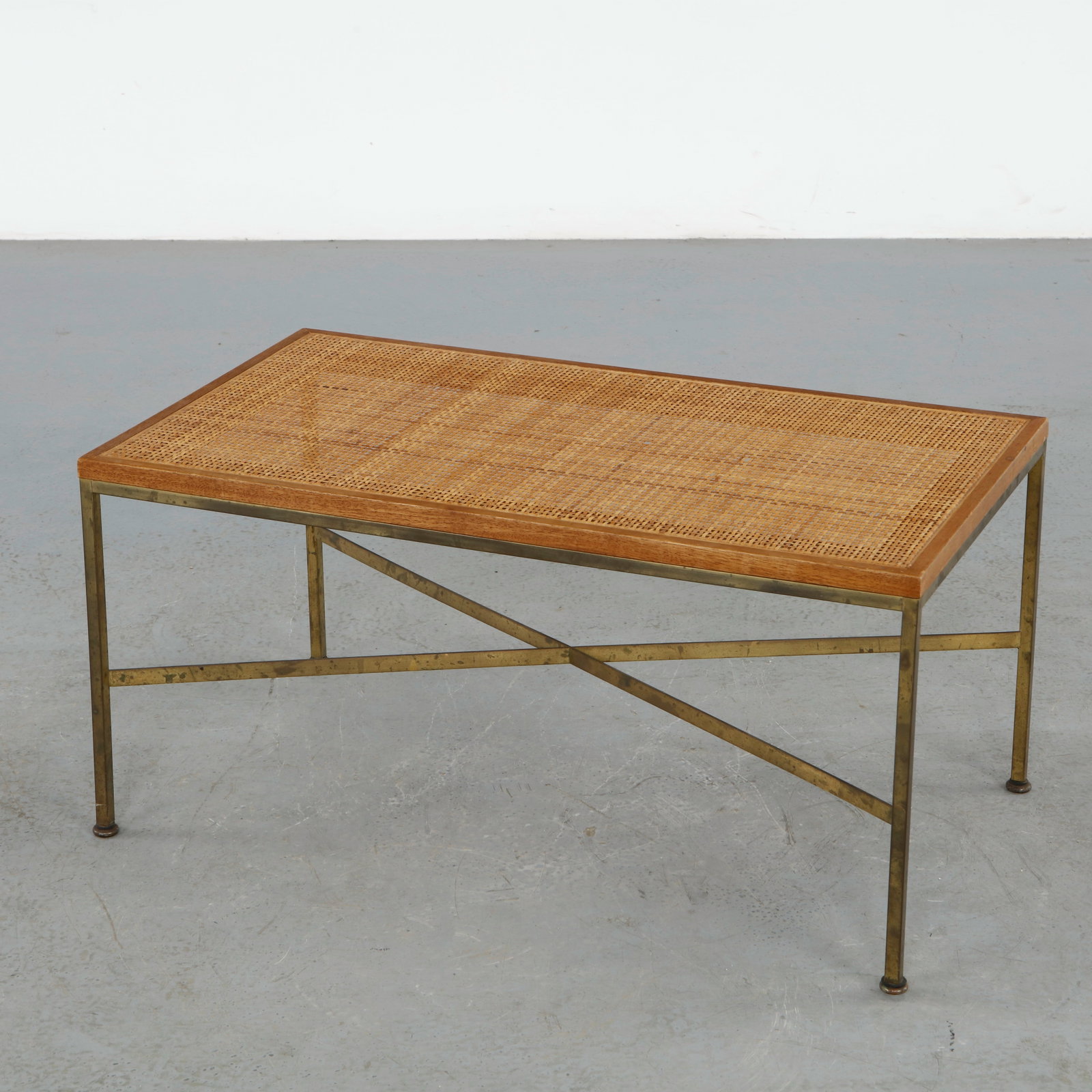 Brass and Cane Coffee Table in the style of Paul McCobb: Featuring a brass frame with an inset woven cane shelf, emphasizing lightness and material contrast. A sophisticated design inspired by McCobb clean and functional aesthetic. Height: 15 in. Length: 30