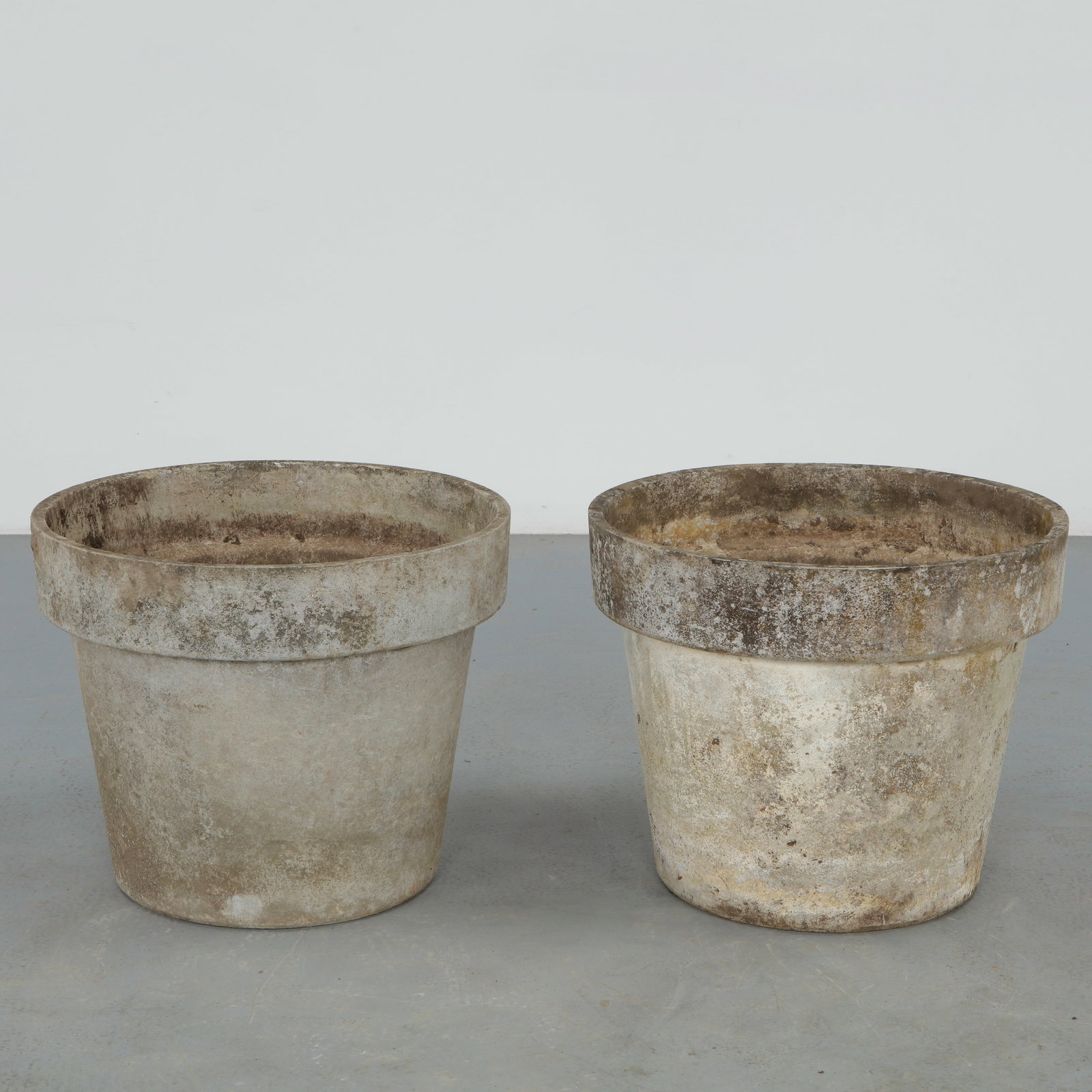 Willy Guhl, Pair of Round Planters, 1960s: Pair of iconic fiber cement planters by Willy Guhl, featuring the designer restrained cylindrical form with pronounced rolled rims. Beautifully weathered surfaces and natural patina enhance their scul