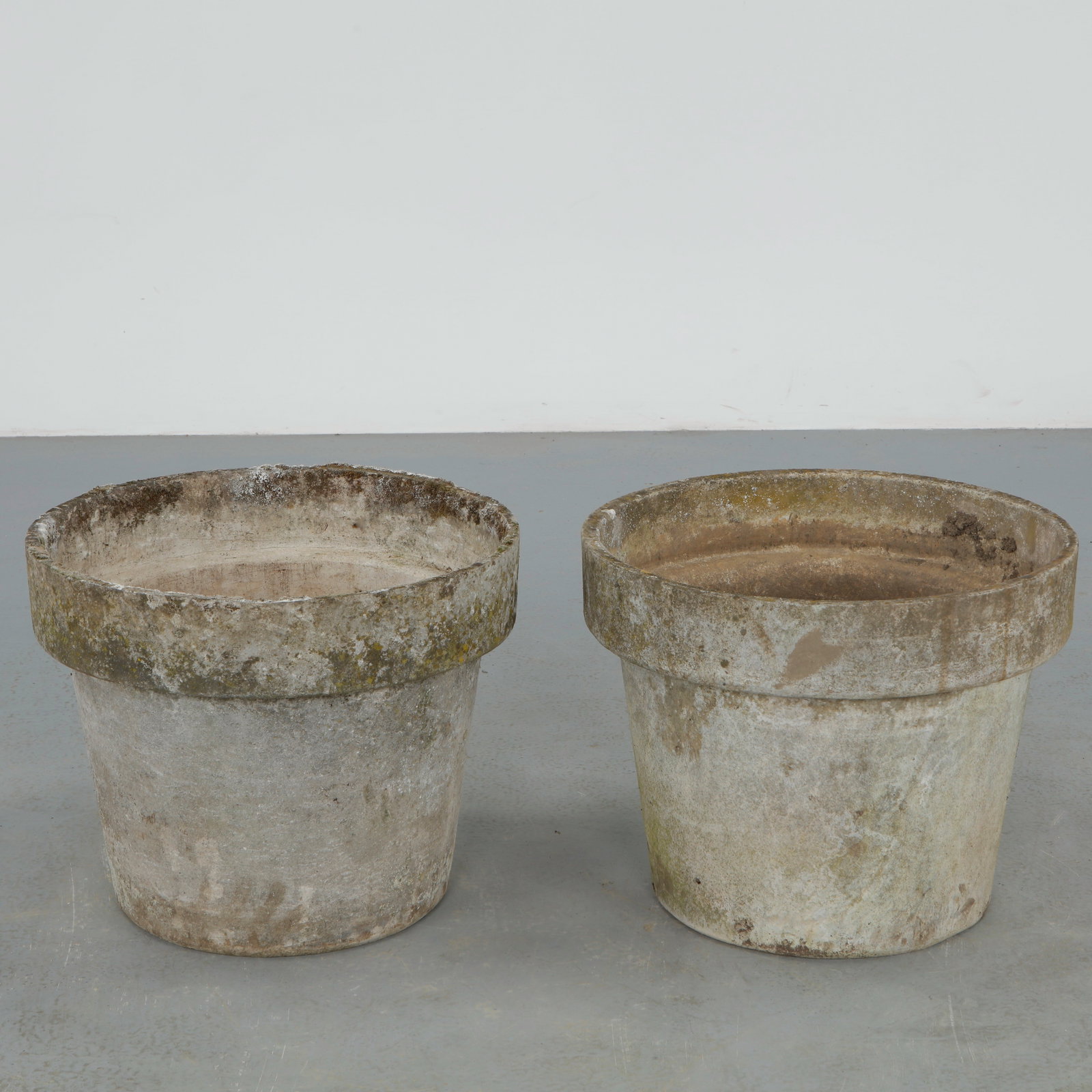 Willy Guhl, Pair of Round Planters, 1960s: Pair of iconic fiber cement planters by Willy Guhl, featuring the designer restrained cylindrical form with pronounced rolled rims. Beautifully weathered surfaces and natural patina enhance their