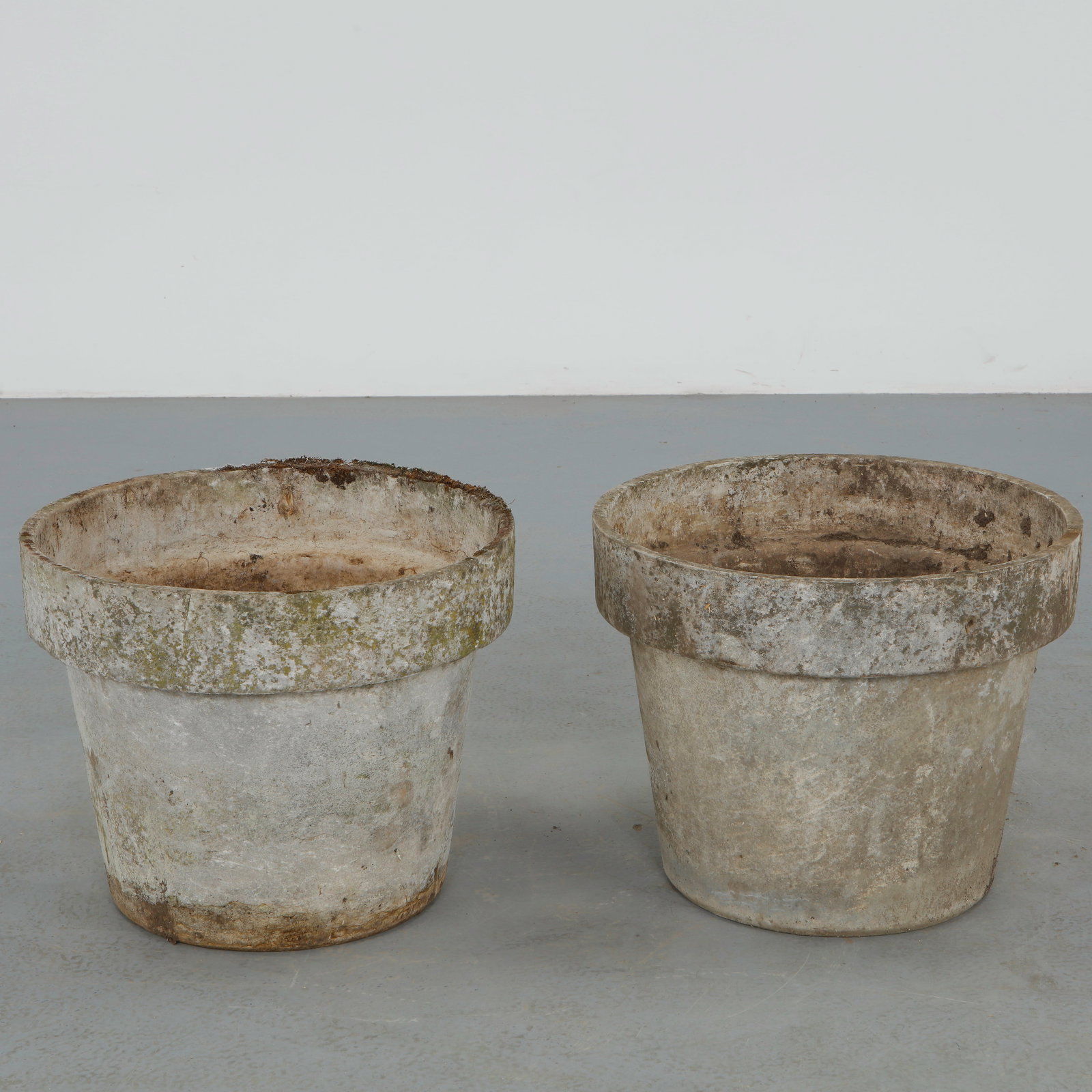 Willy Guhl, Pair of Round Planters, 1960s: Pair of iconic fiber cement planters by Willy Guhl, featuring the designer restrained cylindrical form with pronounced rolled rims. Beautifully weathered surfaces and natural patina enhance their