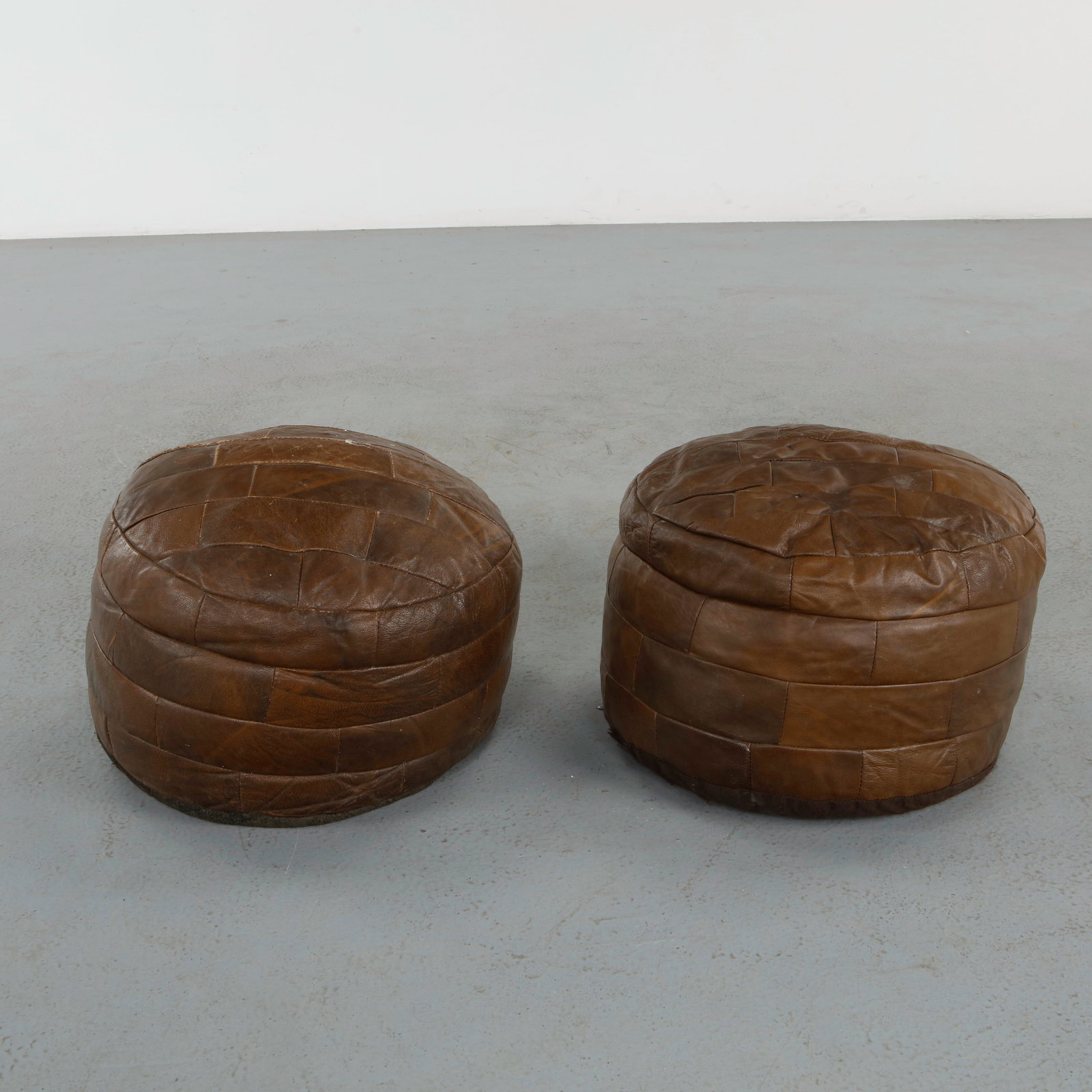 DeÂ Sede, Pair of Leather Ottomans, 1960s: Executed in hand-stitched patchwork leather, these sculptural ottomans exemplify DeÂ Sede signature craftsmanship and supple upholstery. Their brown tones and generous forms invite both comfort and