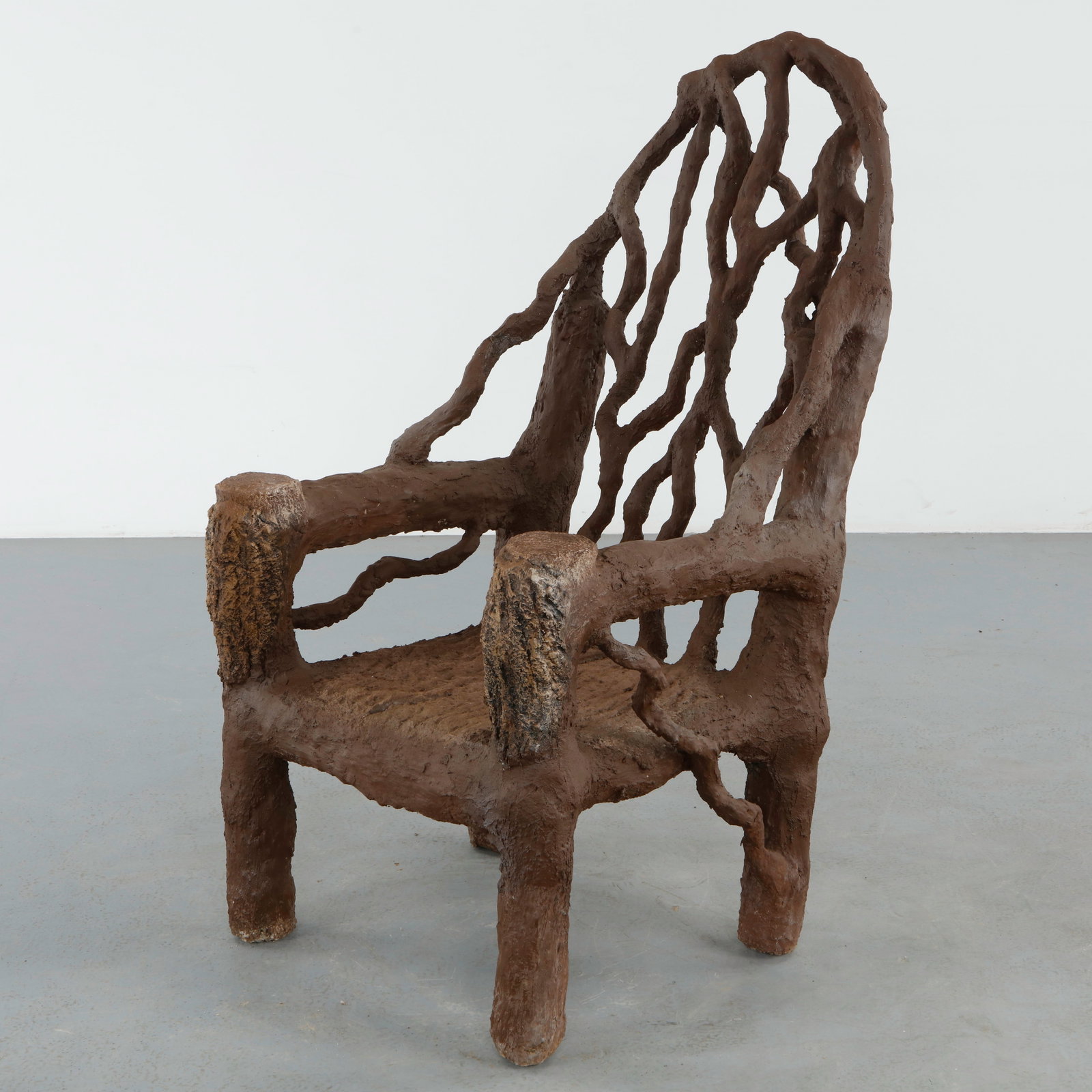 Monumental Faux Bois Sculptural Armchair: Monumental faux bois armchair with a dramatic openwork backrest and deeply textured bark like surfaces. The sculptural composition reflects the expressive craftsmanship associated with fantasy garden