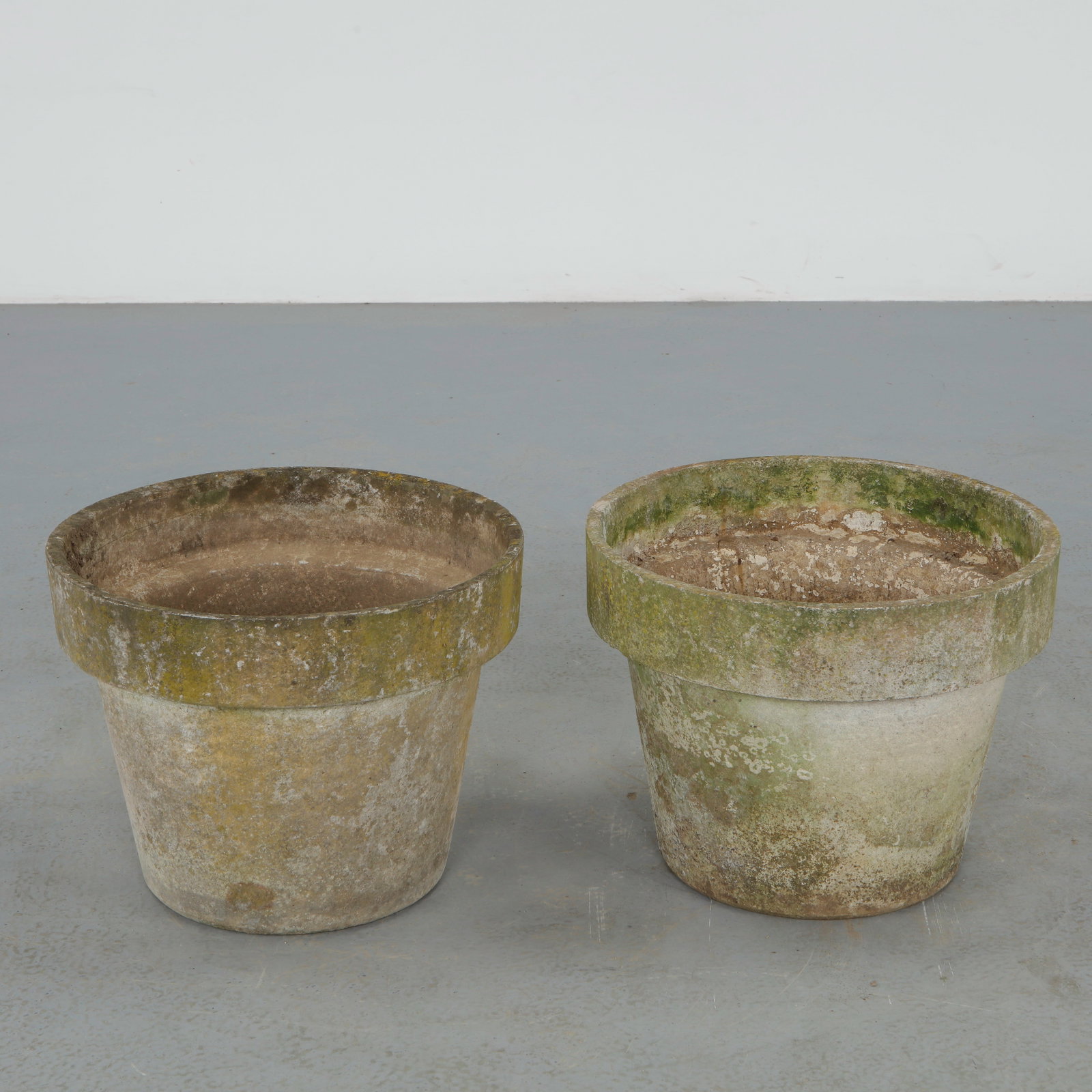 Willy Guhl, Pair of Round Planters, 1960s: Pair of iconic fiber cement planters by Willy Guhl, featuring the designer restrained cylindrical form with pronounced rolled rims. Beautifully weathered surfaces and natural patina enhance their scul