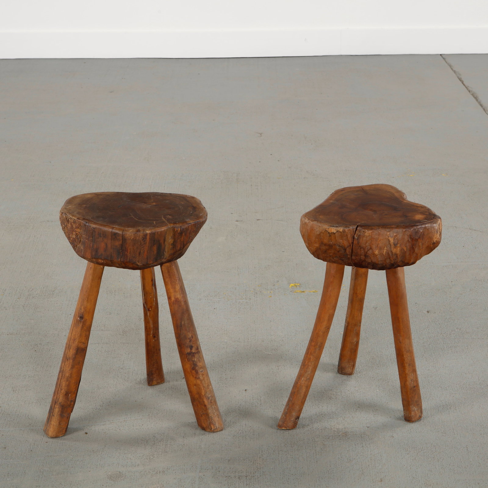 Pair of Brutalist Wood Stools, 1960s: Rare pair of hand-carved solid wood stools featuring organic asymmetrical seats and expressive patina, reflecting a raw Brutalist aesthetic. Height: 16.5 in. Length: 9 in. Width: 10 in.