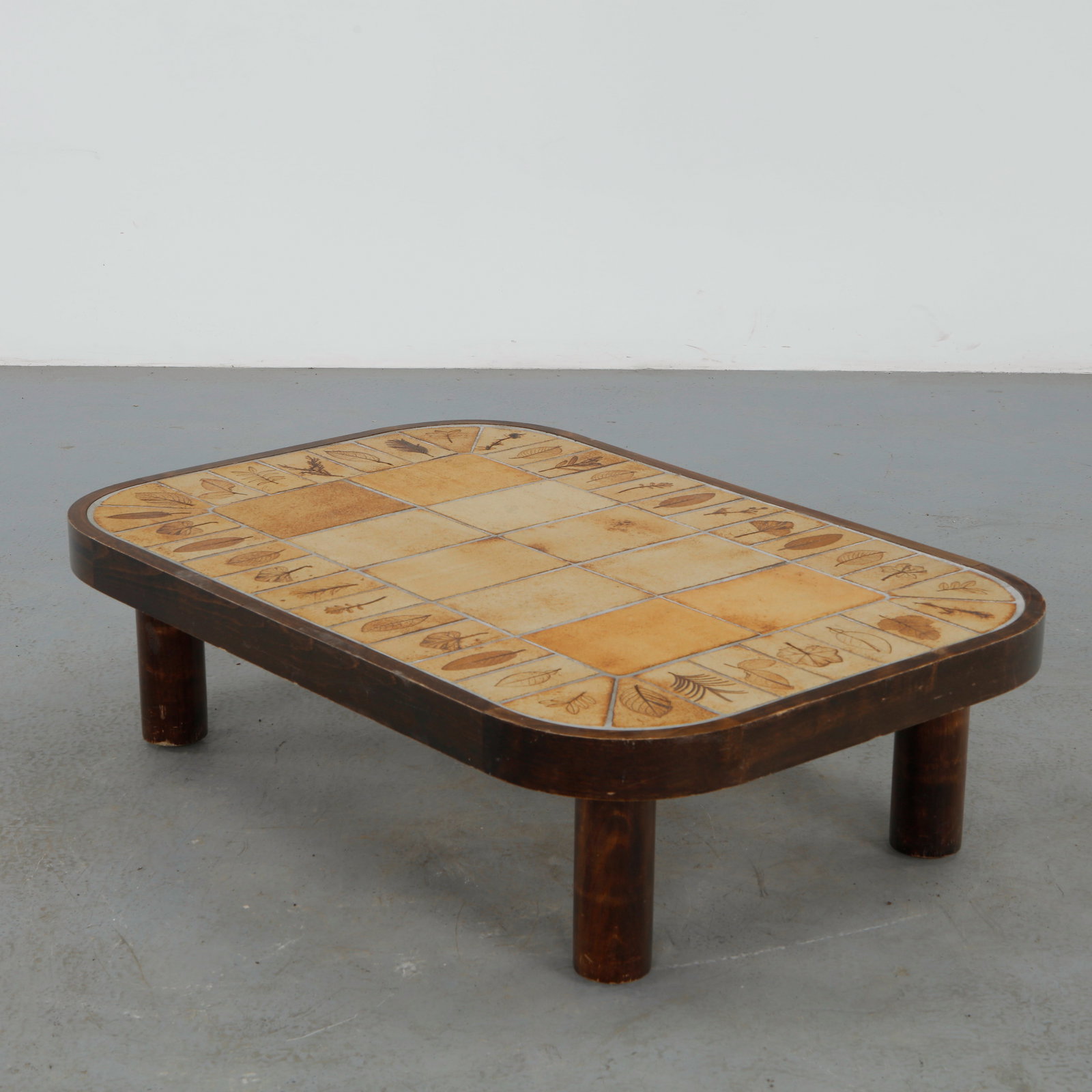 Roger Capron, Rectangular Coffee Table, Signed, 1960s: A ceramic coffee table featuring a tile top decorated with stylized leaf motifs, characteristic of Capronâ€™s Vallauris production. The earthy palette and graphic composition reflect the