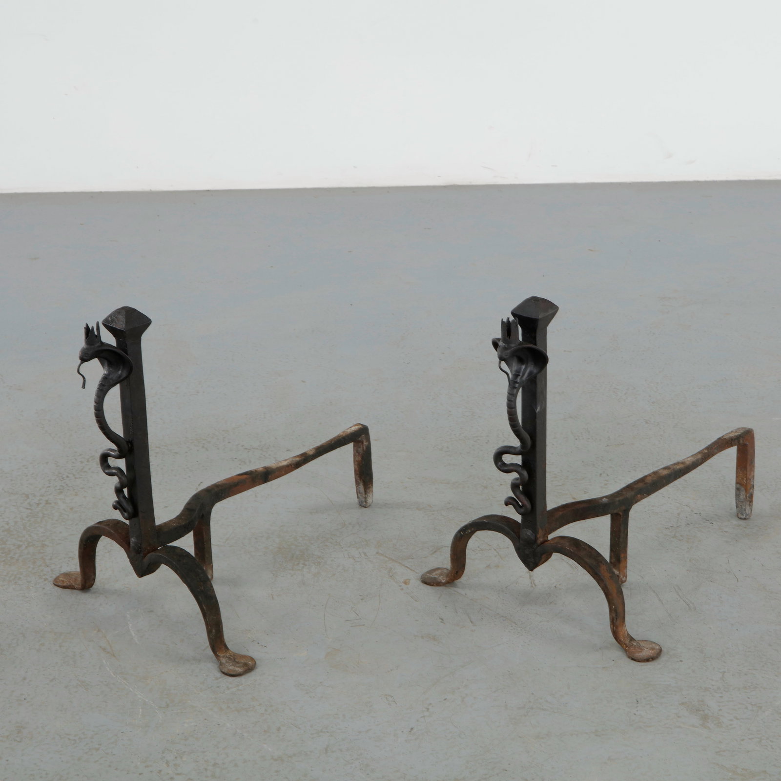 Pair of Italian Wrought Iron Snake Andirons, 1920s: Decorative pair of wrought iron andirons featuring hand forged serpent motifs with expressive scrolling details and hammered surfaces. A rare example of early twentieth century Italian ironwork