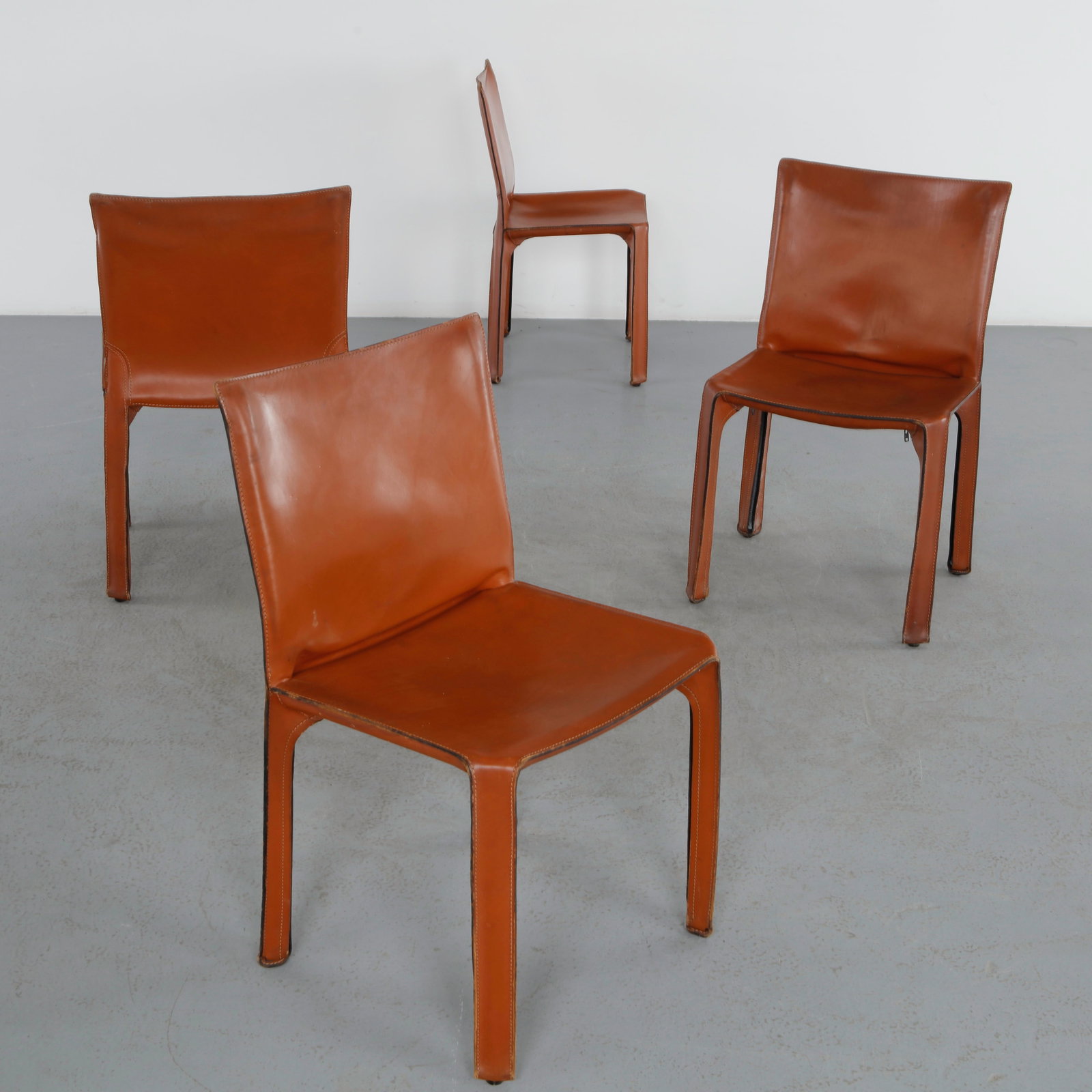 Mario Bellini for Cassina Italy, Set of Four Red leather CAB Dining Chairs, 1970s: Designed by Mario Bellini for Cassina, these iconic CAB chairs feature saddle leather stretched over a concealed steel frame. A landmark design of the 1970s, celebrated for its elegant construction an