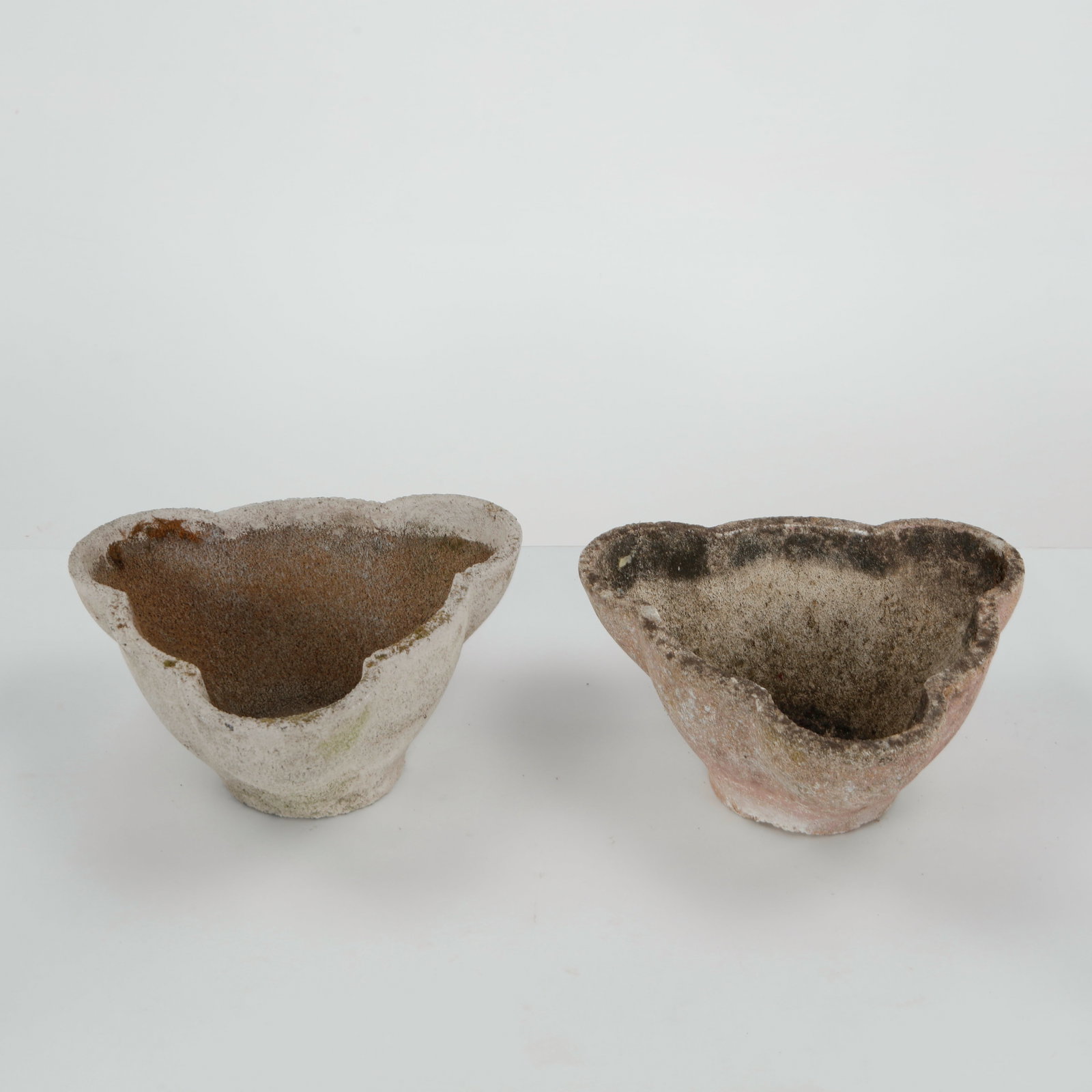 Pair of Scalloped Cast Stone Planters, 1960s: A charming pair of cast stone planters with organic, scalloped edges. Their soft curves and aged patina evoke the elegance of mid-century garden design. Width: 15 in. Length: 15 in. Height: 8 in.