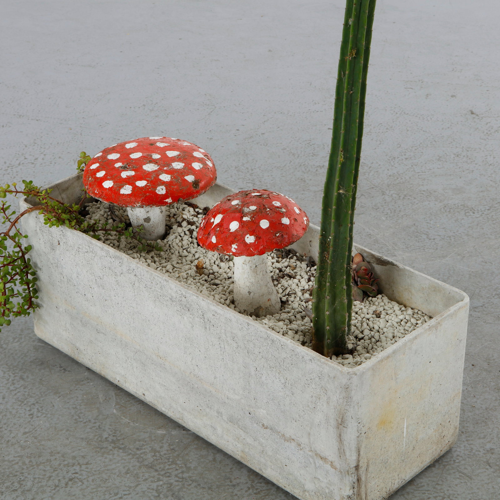 Pair of Vintage Concrete Garden Mushrooms, Fly Agaric Style: pair of concrete garden mushroom ornaments in the classic fly agaric toadstool style, with bold red-and-white spotted caps atop tapering white stems, each mounted on a metal spike for placement in soi
