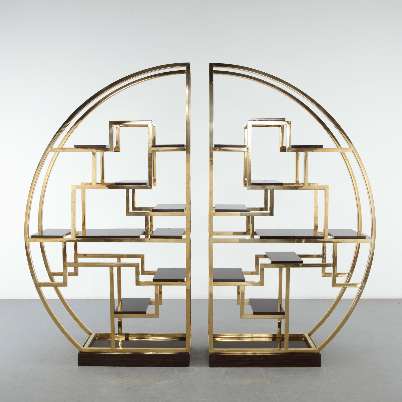 Milo Baughman Fan-Form Brass Library Shelving: A dramatic pair of semicircular library in polished brass by Milo Baughman, their fan-shaped frames enclosing an asymmetric grid of ebony-finished shelves. Each unit splits into two quarter-round sect