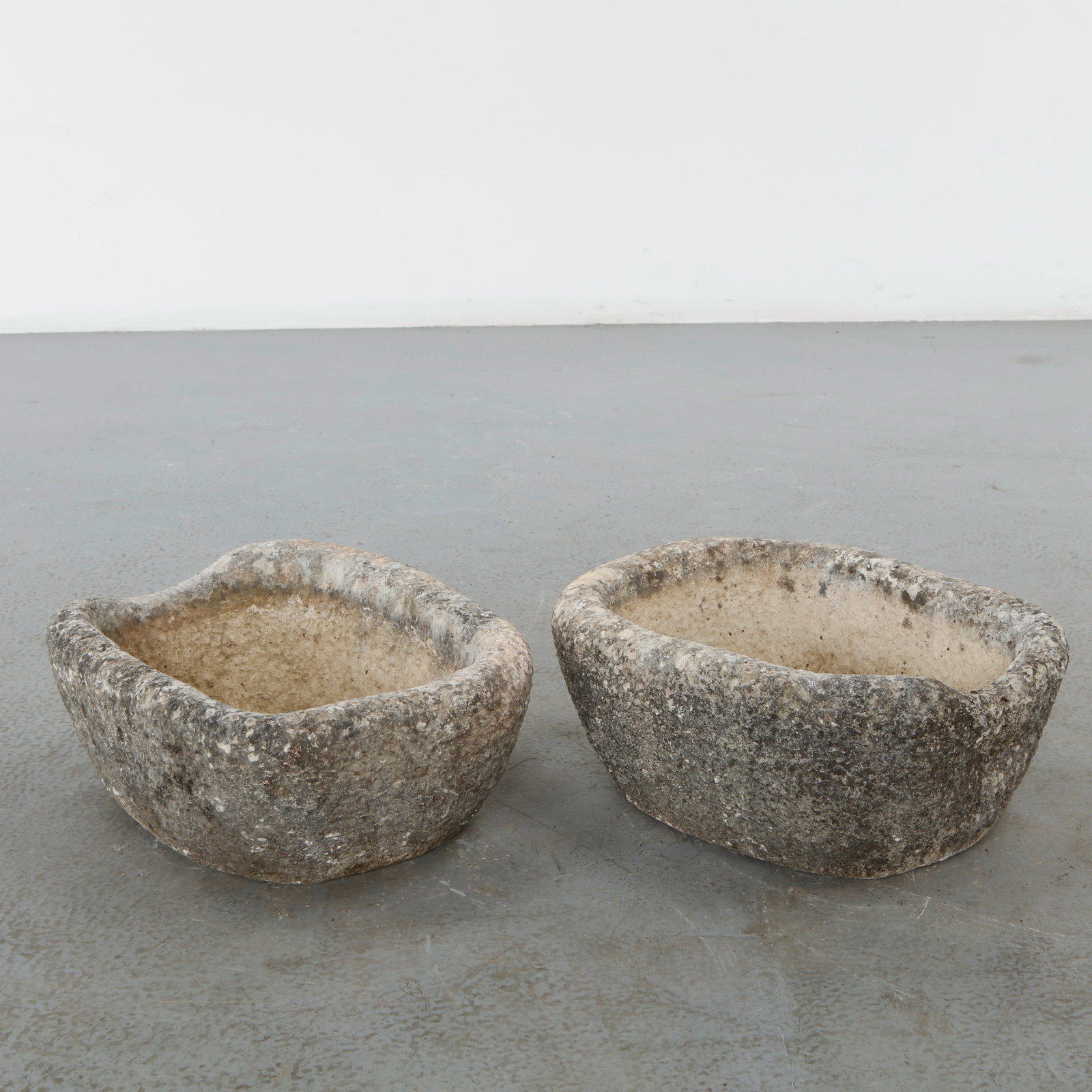 Pair of 19th Century Stone Trough Planters: Hand-carved from a single block of stone, this sculptural planter features an organic silhouette and a richly weathered surface developed through years of outdoor exposure. A distinctive architectural