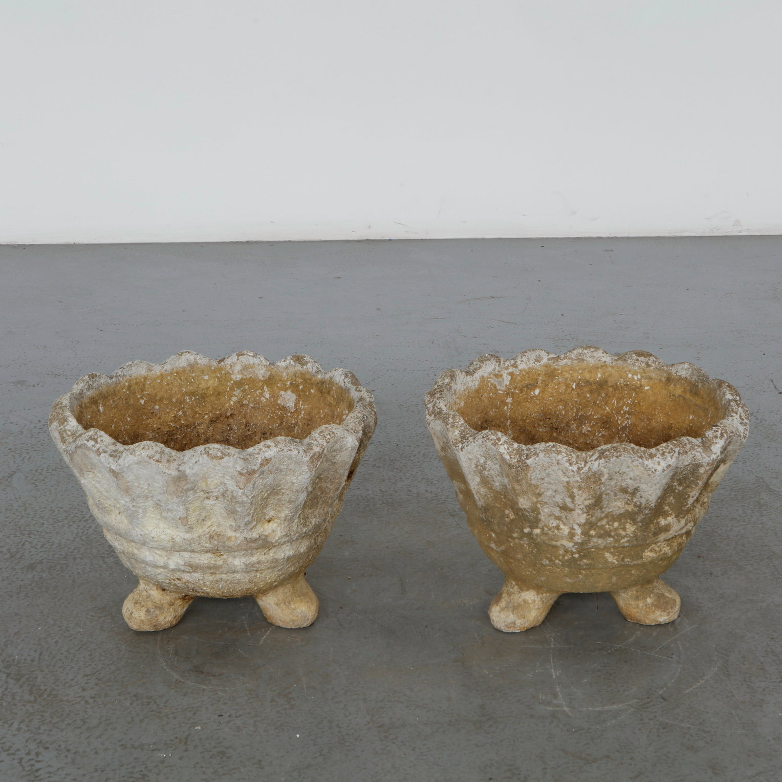 Pair of Freeform Concrete Planters, 1960s: A sculptural pair of freeform concrete planters featuring organic shell inspired silhouettes and deeply textured surfaces. Their weathered patina and expressive forms bring a strong architectural pres