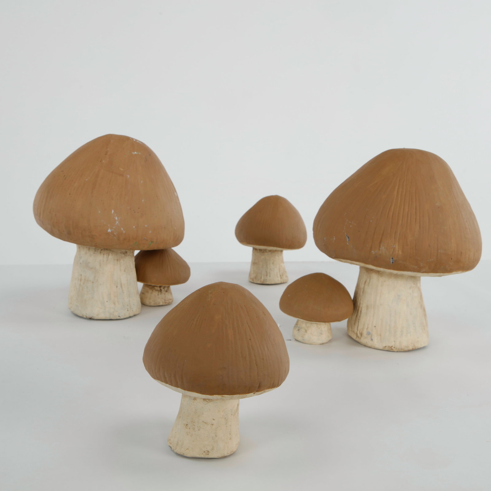 Set of Six Cast Stone Garden Mushrooms, 1960s: A whimsical set of six cast stone garden mushrooms in graduated sizes, featuring hand-painted caps and textured stems. Ideal for creating a playful woodland accent in gardens and landscaped settings. 