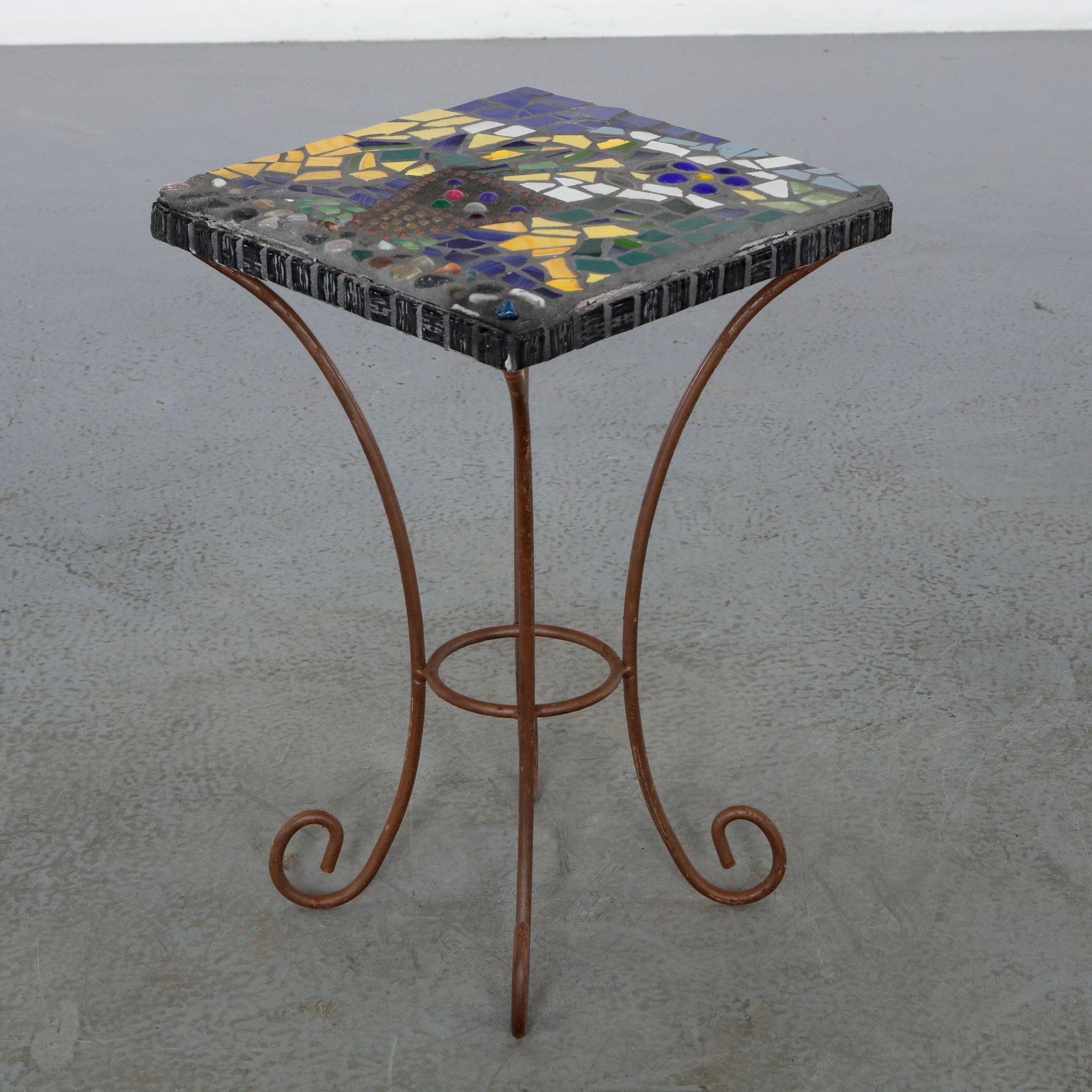 Mosaic Tile Side Table, 1960s: Decorative side table featuring a hand executed mosaic top composed of colorful ceramic elements. The lively composition is enhanced by an elegant wrought iron base. Height: 19.5 in. Length: 12.5 in. 