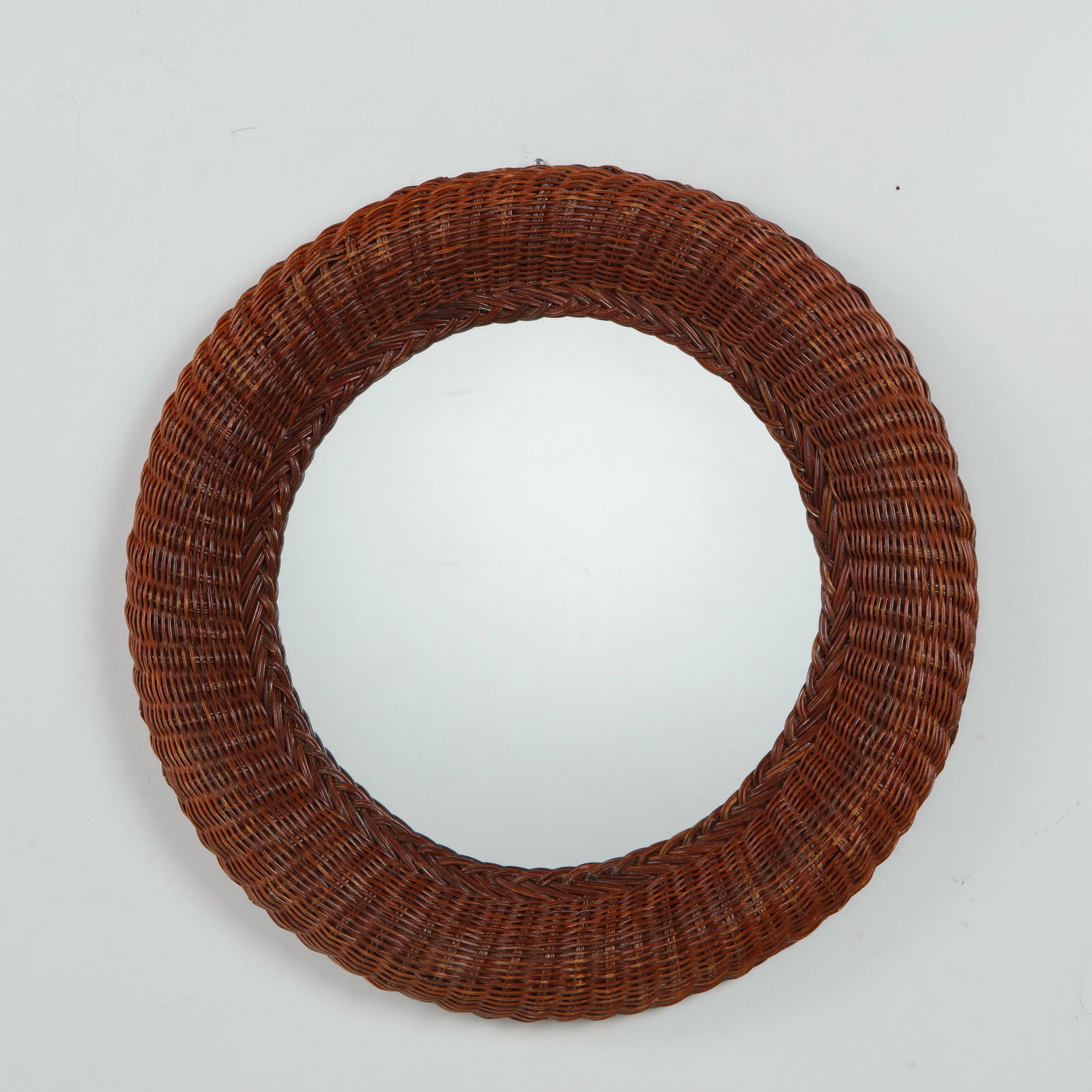 Woven Wicker Mirror, Mid-Century: France, mid-20th century. Circular mirror plate set within a thick hand-woven rattan frame, braided in a herringbone pattern. Rich, warm patina throughout. Diameter: 23 in.