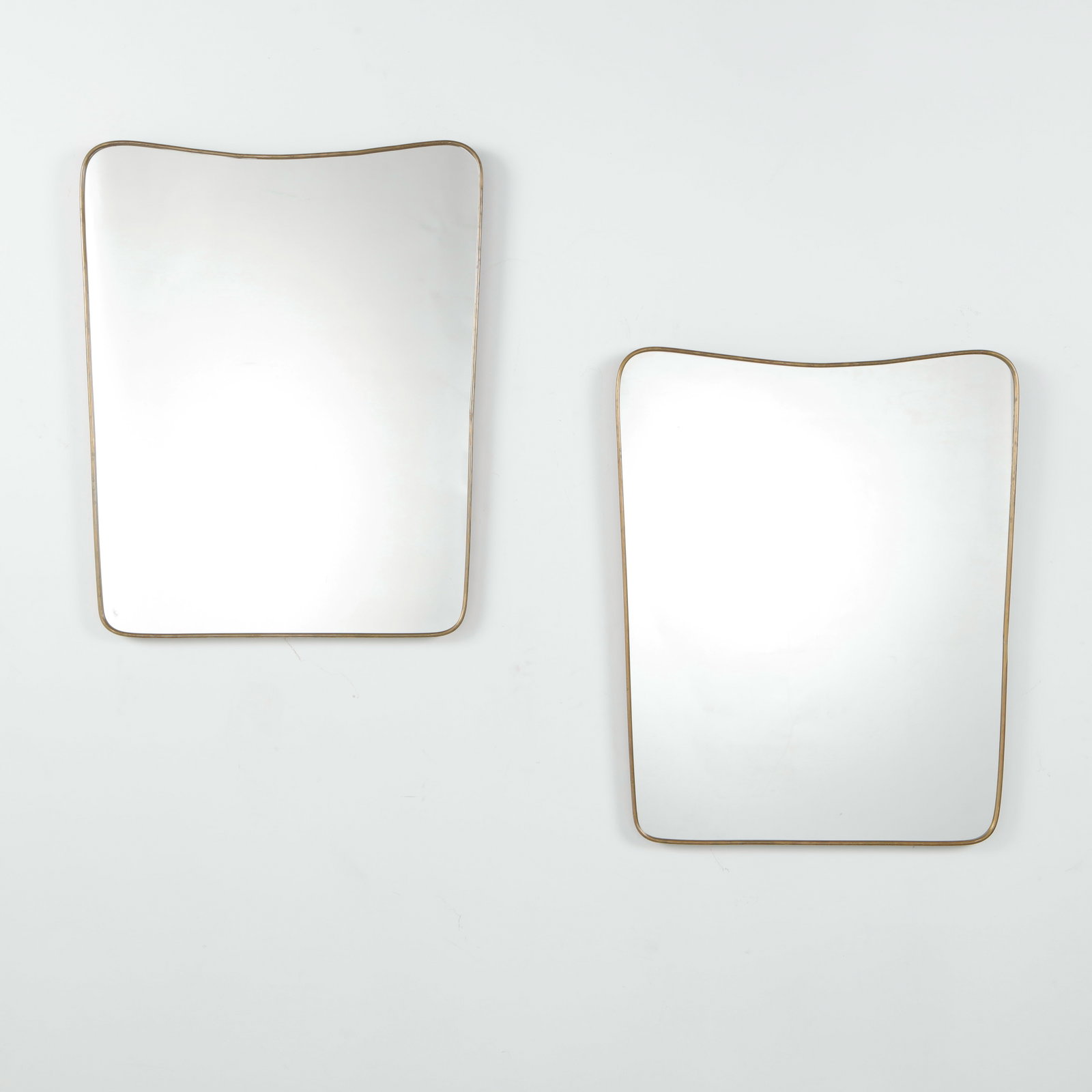 Pair of Italian Brass Mirrors, Wave-Top Rectangular Form, 1950s: A pair of Italian mid-century mirrors with slender brass frames, in a rectangular form with a gently undulating top edge and rounded corners. Sold as a pair. Height: 25 in. Length: 31 in. Width: in.