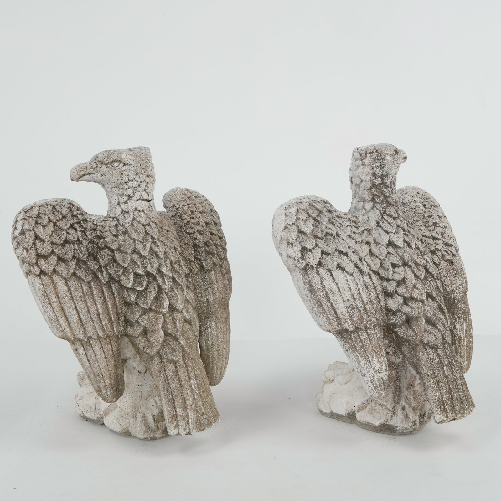 Pair of Cast Stone Eagle Garden Sculptures, 1960s: A striking pair of cast stone eagle sculptures, finely modeled with detailed plumage and a naturally weathered patina. Their commanding presence makes them exceptional architectural or garden