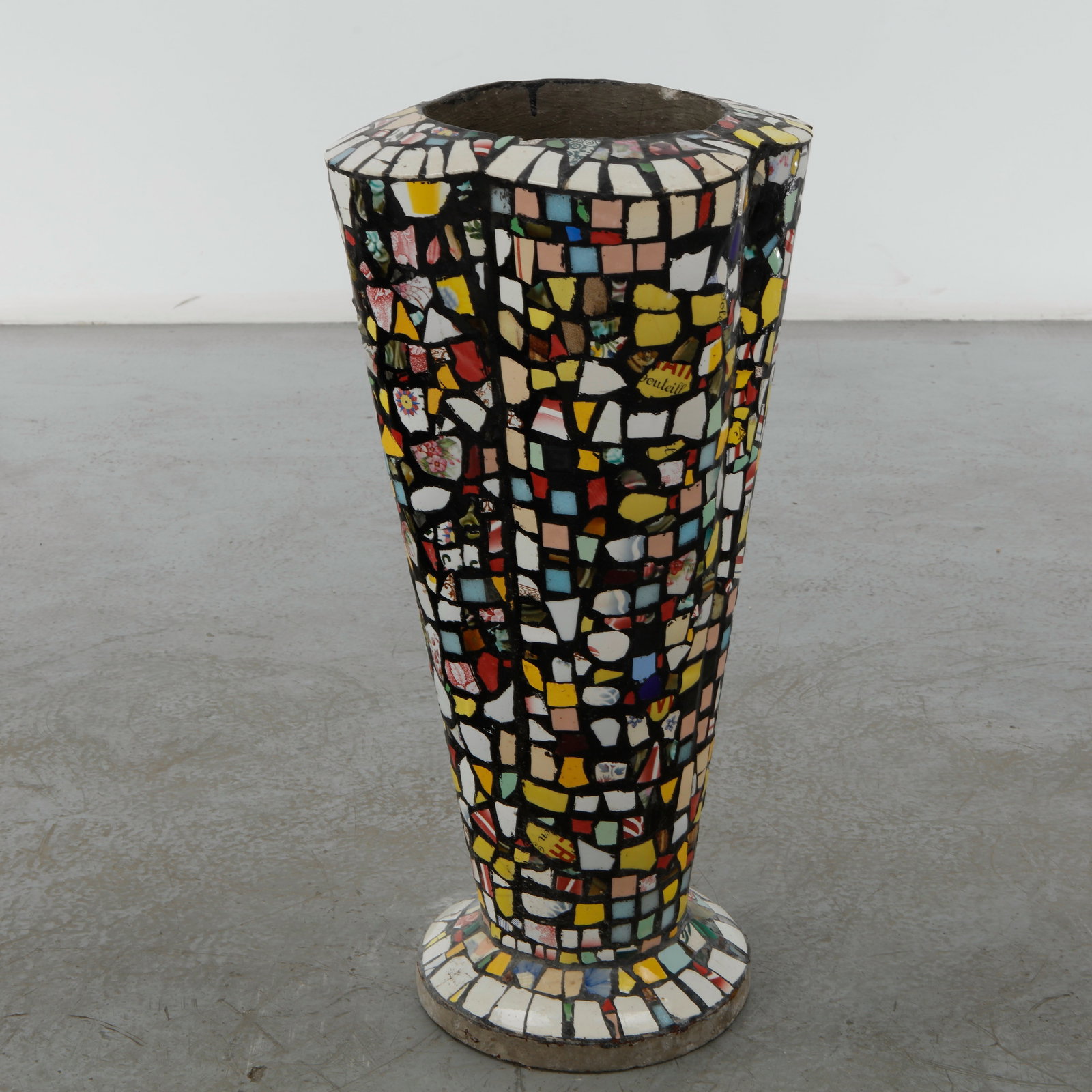Mosaic Ceramic Planter, 1960s: Constructed from cement, this tall, flared planter is faced in a dense mosaic of broken ceramic tile fragments, including floral patterned porcelain shards, in a palette of yellow, red, white, and blu