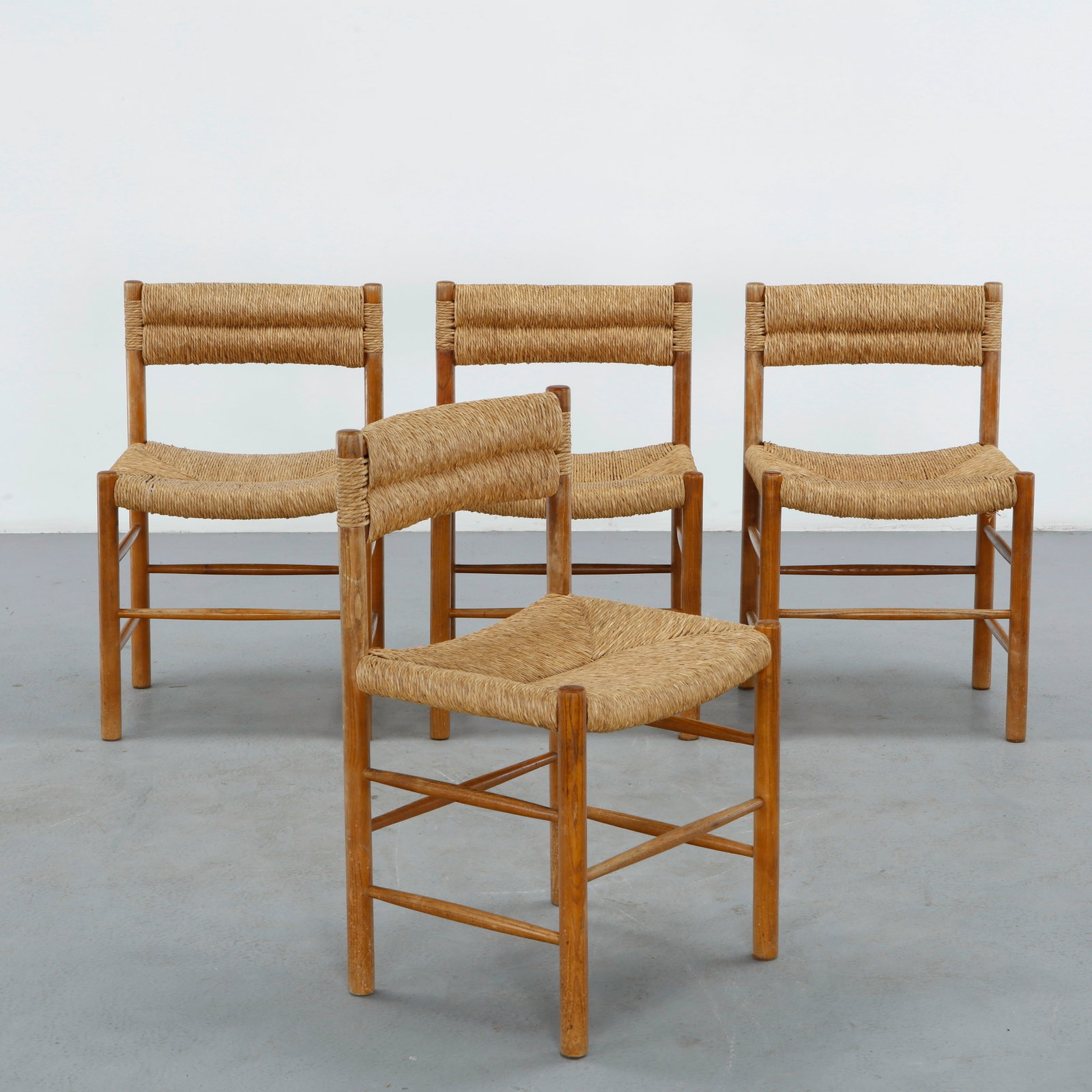 Charlotte Perriand, Set of Four Dordogne Dining Chairs, 1950s: Four iconic Dordogne chairs designed by Charlotte Perriand, with solid wood frames and cylindrical legs, the backrest wrapped in banded natural rope and the seat hand woven in rush, a clean, rustic-mo