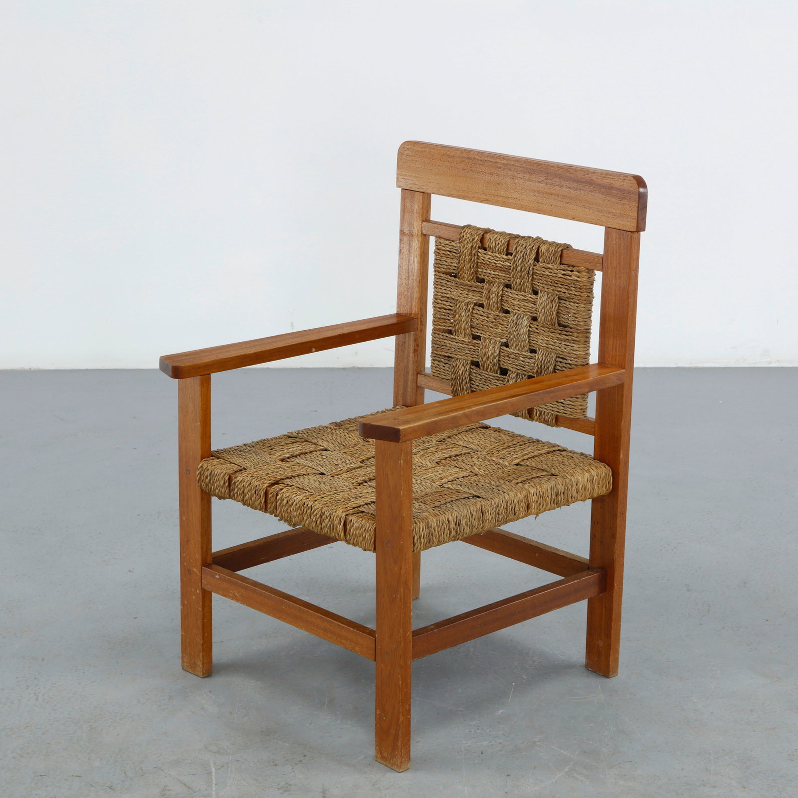 Wood and Rope Chair attributed to Audoux Minet, 1950s: A single armchair attributed to Audoux Minet, with a warm wood frame and both the seatback panel and seat hand-woven in natural rope, restrained, organic design in the duo signature style. Height: 29 