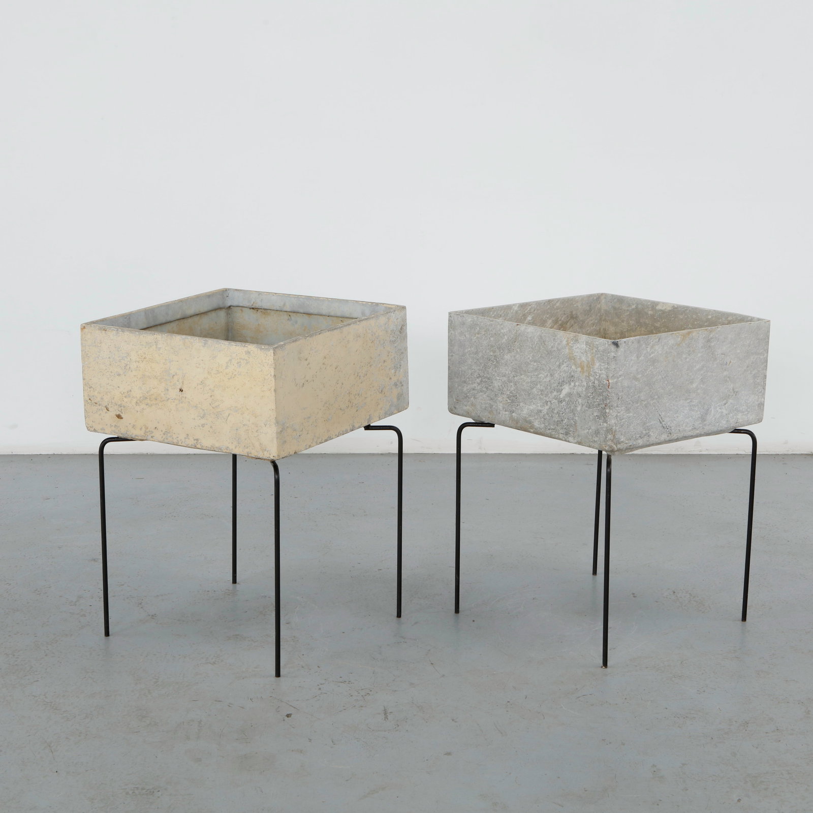 Willy Guhl, Pair of Square Planters on Metal Stands, 1960s: A pair of square planters in fiber cement, each raised on its original slender iron rod stand. One planter in cream, the other in grey, both lightly weathered. Height: 27 in. Length: 19.25 in. Width: 