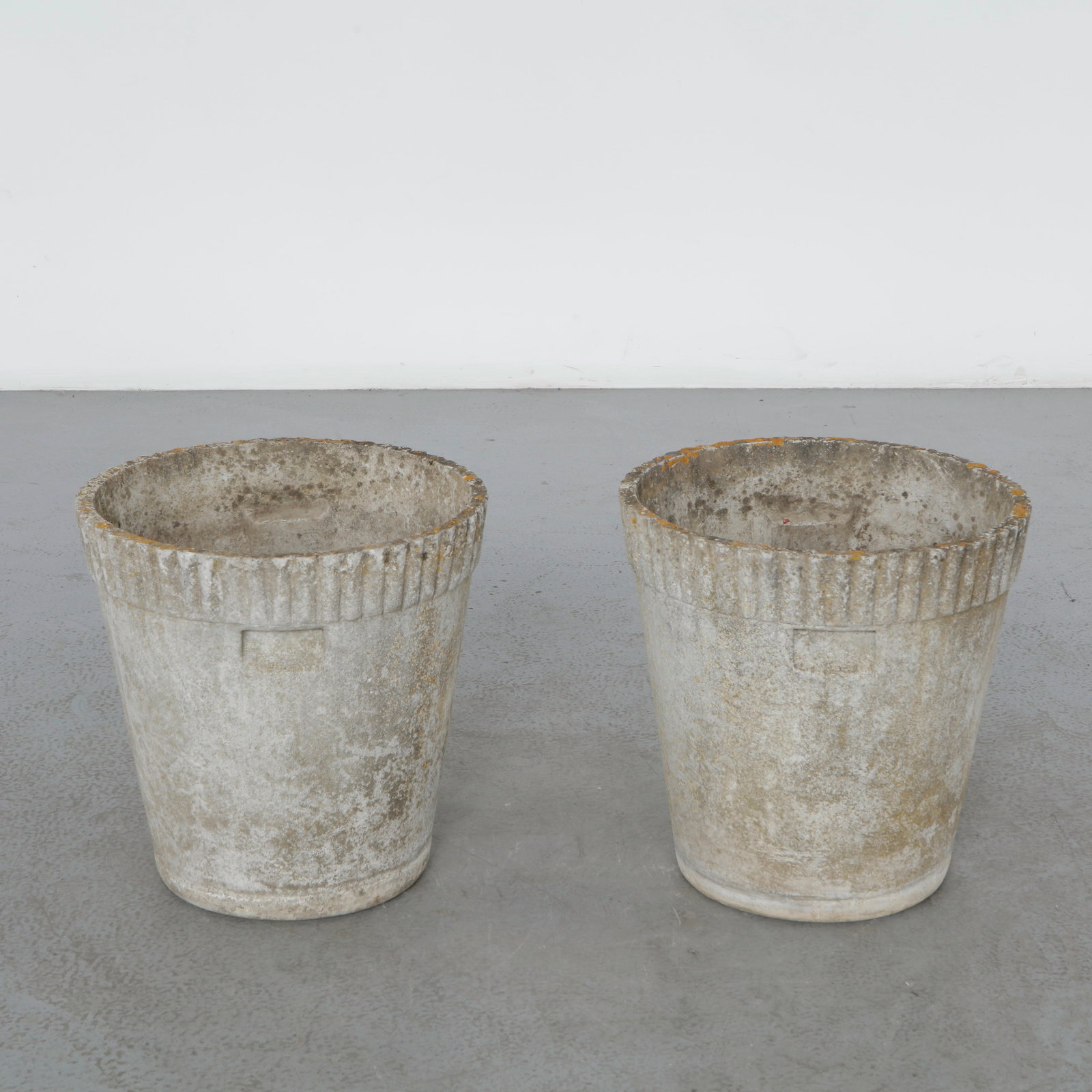Willy Guhl, Pair of Round Concrete Planters, 1960s: Classic 1960s round planters by Willy Guhl, with ribbed detailing along the rim. Timeless silhouettes for elegant garden design. Height: 18.5 in. Diameter: 18 in.