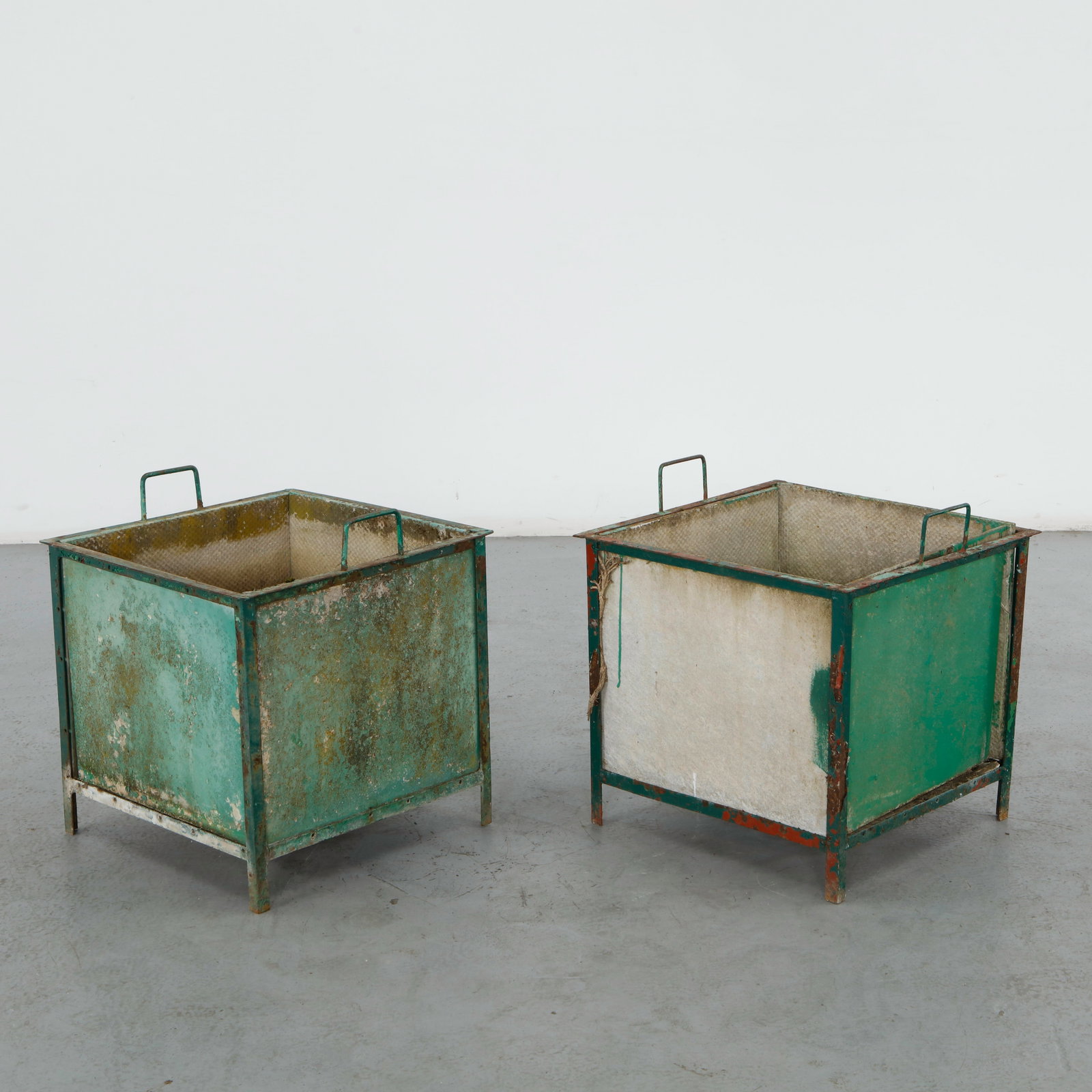 Willy Guhl, Pair of Cubic Planters with Metal Frames, 1960s: A pair of square planters in fiber cement, each encased in a painted iron armature with folded loop handles to each side. Heavy oxidation and paint loss to the metalwork, retaining traces of green and
