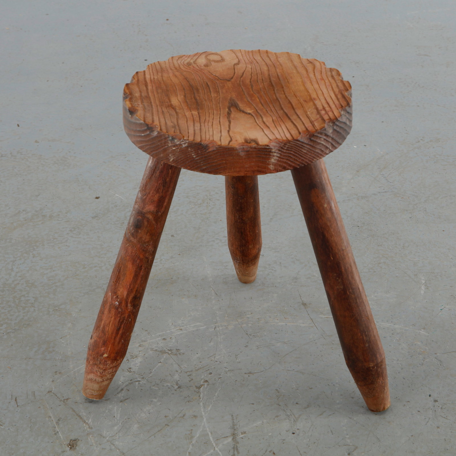 Rustic Tripod Stool, 1960s: Handcrafted tripod stool executed from solid wood, featuring a sculpted circular seat and rounded legs. Its primitive form and expressive grain exemplify the enduring appeal of vernacular craftsmanshi
