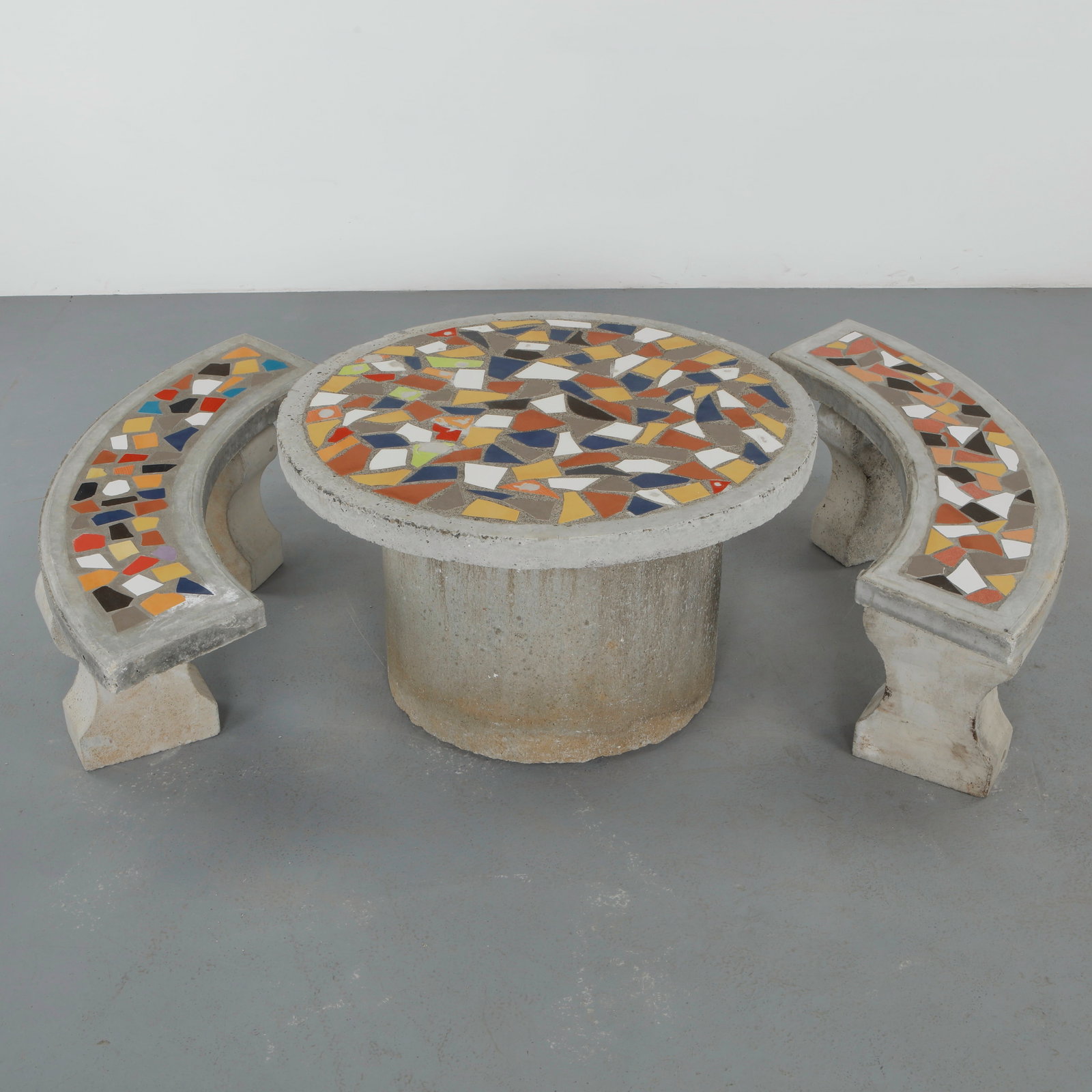 Multicolored Mosaic Tile Dining Set, 1960s: Comprising a circular table and two curved benches, each element executed in concrete with vibrant mosaic surfaces. The ensemble creates a cohesive and playful outdoor dining arrangement. Table: Heigh
