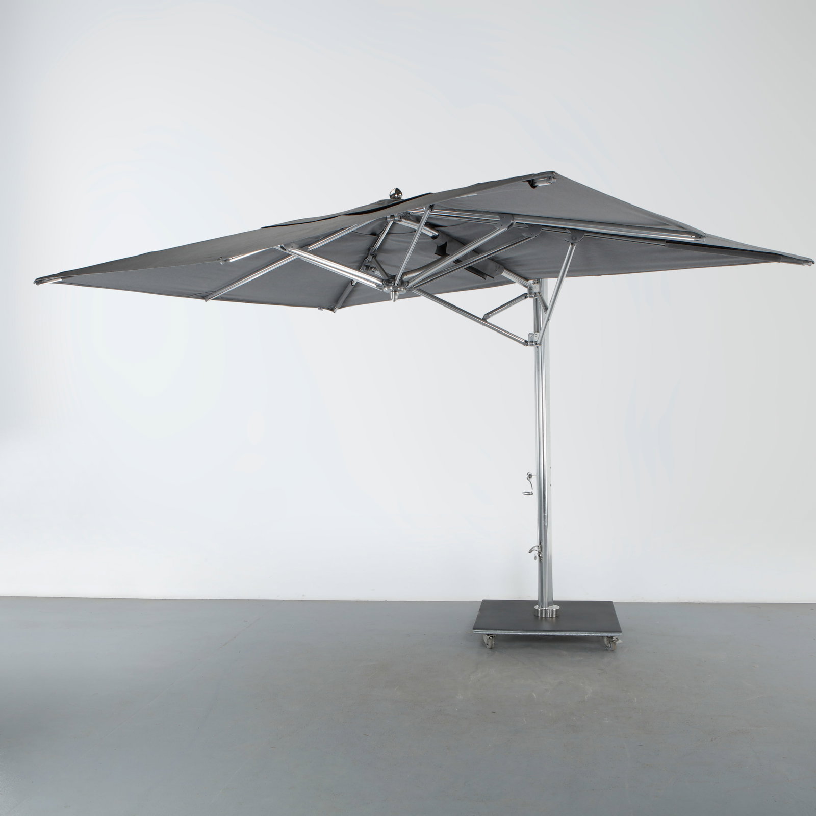 Tuuci, Ocean Master Max Cantilever Umbrella with Wheels: A matching cantilevered umbrella in brushed stainless steel with a gray square canopy, its heavy base fitted with locking casters for easy repositioning. Length: 108 in. Depth: 108 in. Height: 104 in.
