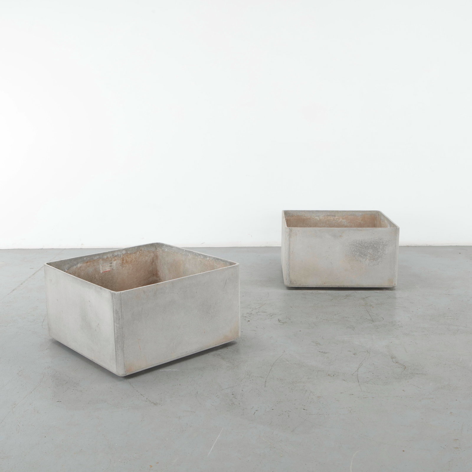 Willy Guhl, Pair of Monumental Square Planters, 1960s: A monumental pair of square concrete planters attributed to Willy Guhl, distinguished by their pure geometric volumes and generously proportioned forms. The restrained construction and naturally weath