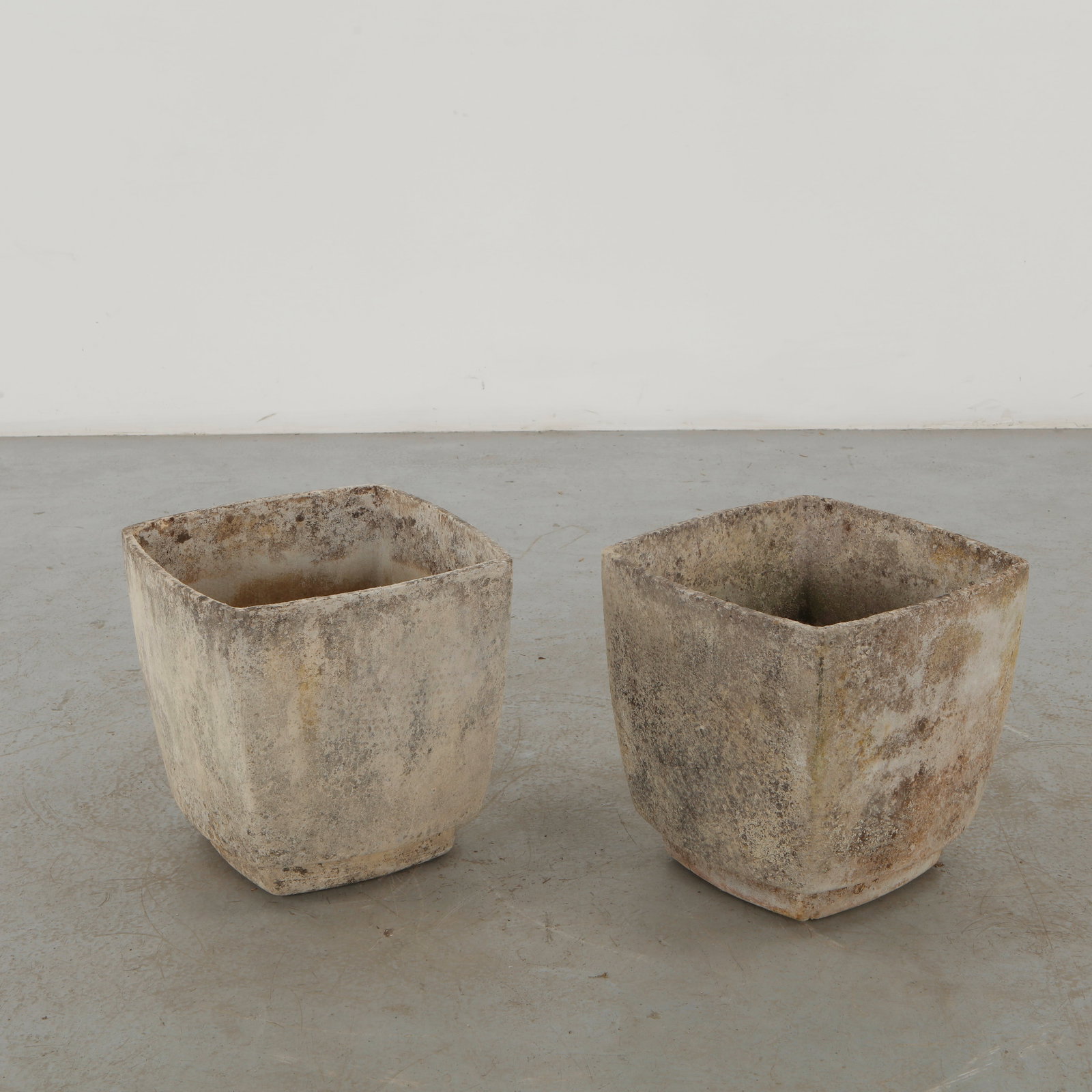 Willy Guhl, Pair of Square Concrete Planters, Switzerland, 1960s: A pair of substantial square concrete planters attributed to Willy Guhl, distinguished by their restrained geometric volumes and softly weathered surfaces. Their monumental simplicity reflects Guhl