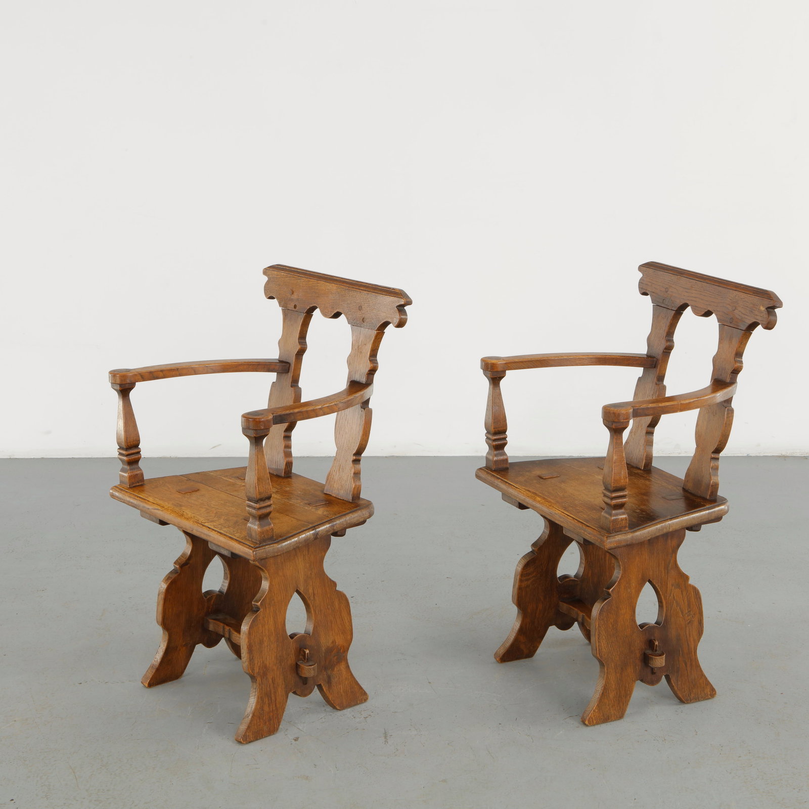 Pair of Brutalist Wood Armchairs, 1960s: A striking pair of sculptural wooden armchairs featuring carved openwork backs, broad armrests and highly articulated pedestal bases. The deeply shaped timber and ornamental cutouts create a monumenta