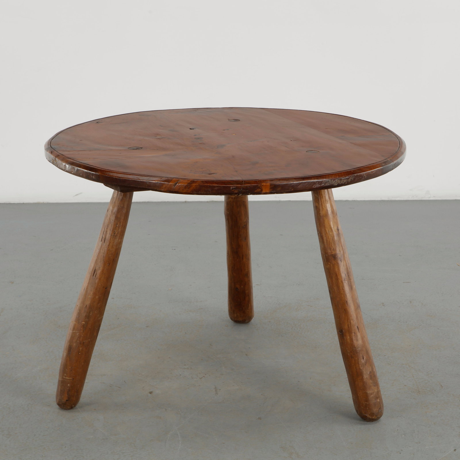 Brutalist Wood Dining Table, 1960s: A substantial round dining table crafted in solid wood, featuring a broad plank constructed top with pronounced natural grain and a robust three leg base. The heavily worked surface and organic constr