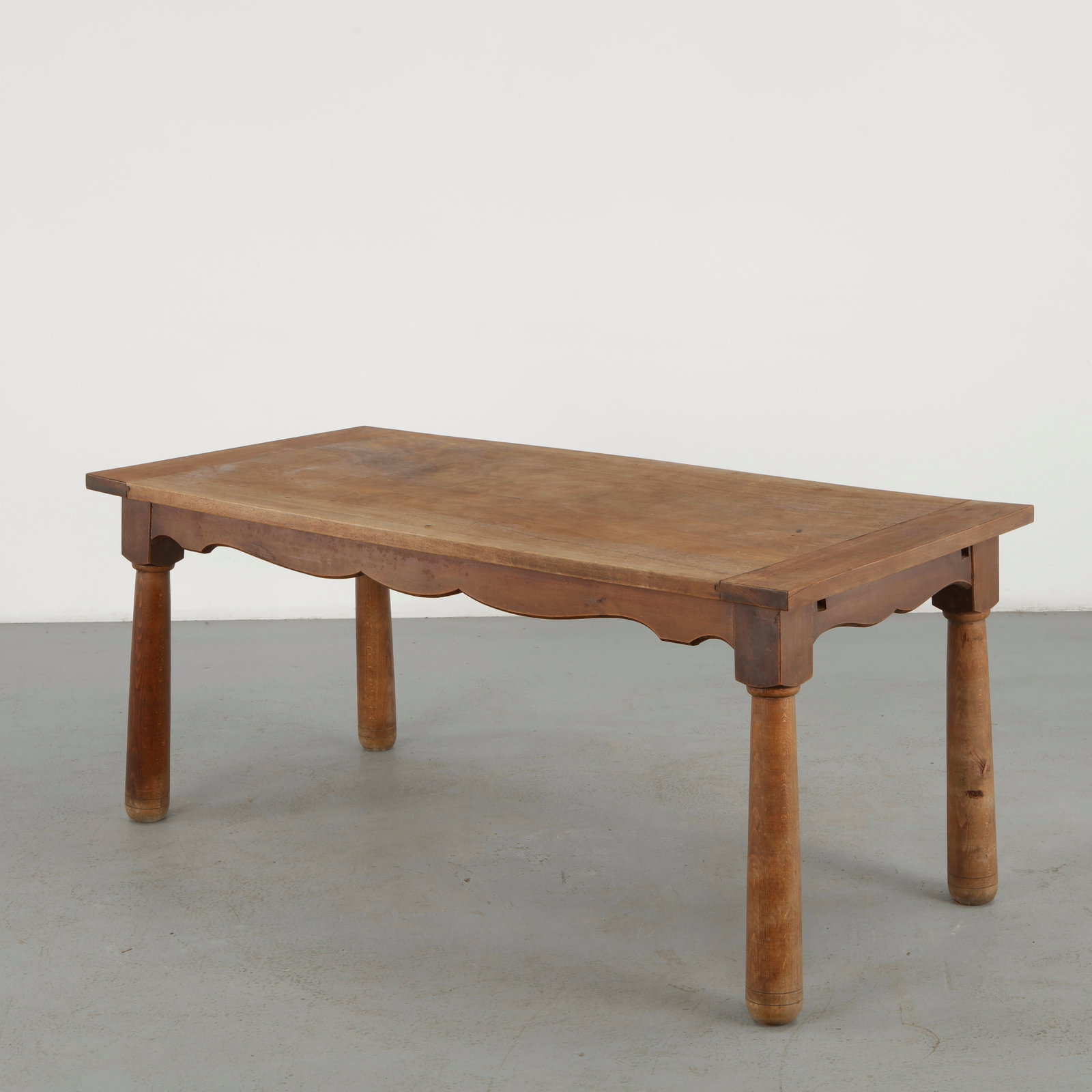 Italian Wood Farm Table, 19th Century: A characterful Italian farm table executed in solid wood, distinguished by a generously proportioned plank top and turned legs. The scalloped apron and pronounced surface patina preserve the rustic cr