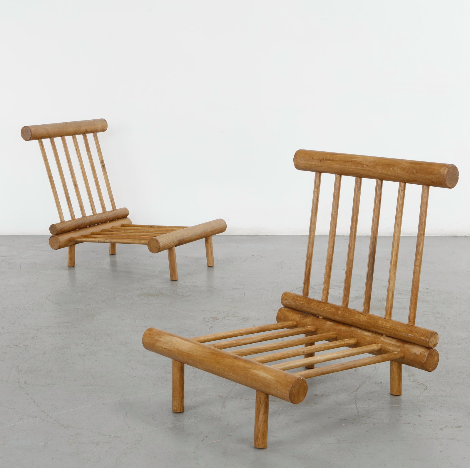Charlotte Perriand, Pair of La Cachette Oak Fireside Chairs, 1960s: Pair of low fireside chairs executed in solid oak with cylindrical structural elements and slatted seat. The robust construction and clear geometry reflect Perriand commitment to honest materials and