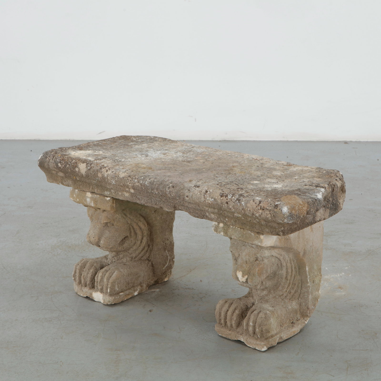 Stone Lion Garden Bench, 1960s: Striking carved stone garden bench supported by two sculptural lion-form legs, each rendered with stylized features and articulated paws. The substantial stone slab displays a richly weathered patina.