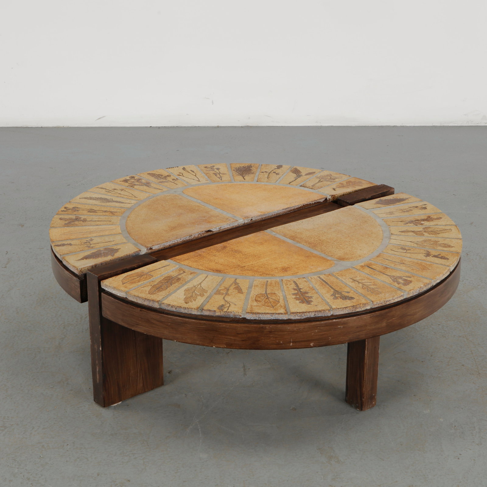 Roger Capron, Round Ceramic and Wood Coffee Table, France, 1960s: A distinctive round coffee table by Roger Capron, featuring a circular wooden structure inset with hand crafted ceramic tiles decorated with botanical motifs. The radial composition and earthy palette