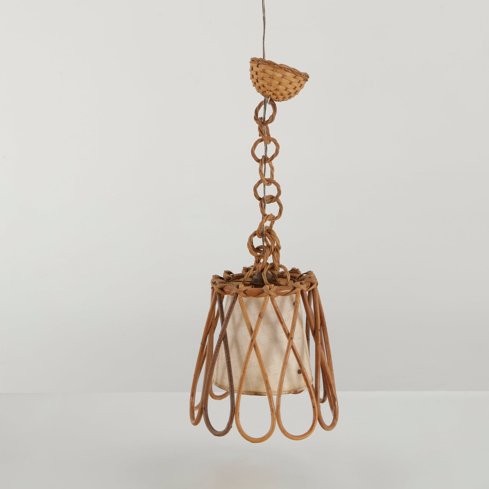 Louis Sognot, Open Rattan Cage Pendant Lamp, 1960s: A rare open-form pendant lamp by Louis Sognot, constructed from slender rattan elements arranged in an elongated cage-like silhouette. The exposed framework allows the woven material to become the pri