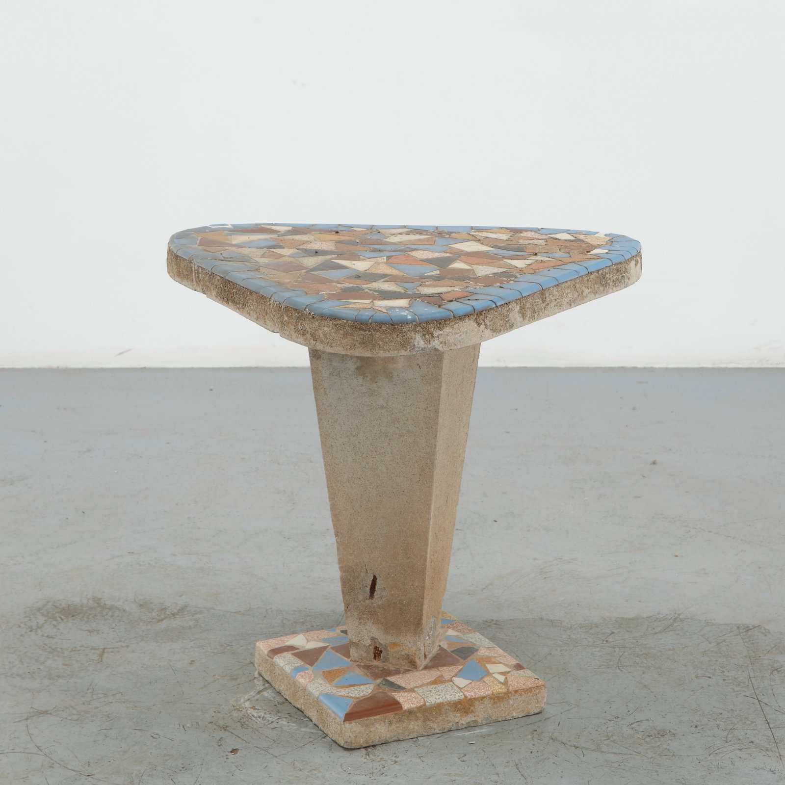 Mosaic Concrete Outdoor Table, 1960s: A distinctive outdoor table executed in concrete, featuring a substantial square top and pedestal base enriched with an irregular mosaic of ceramic fragments in muted blue, terracotta, cream, and brow