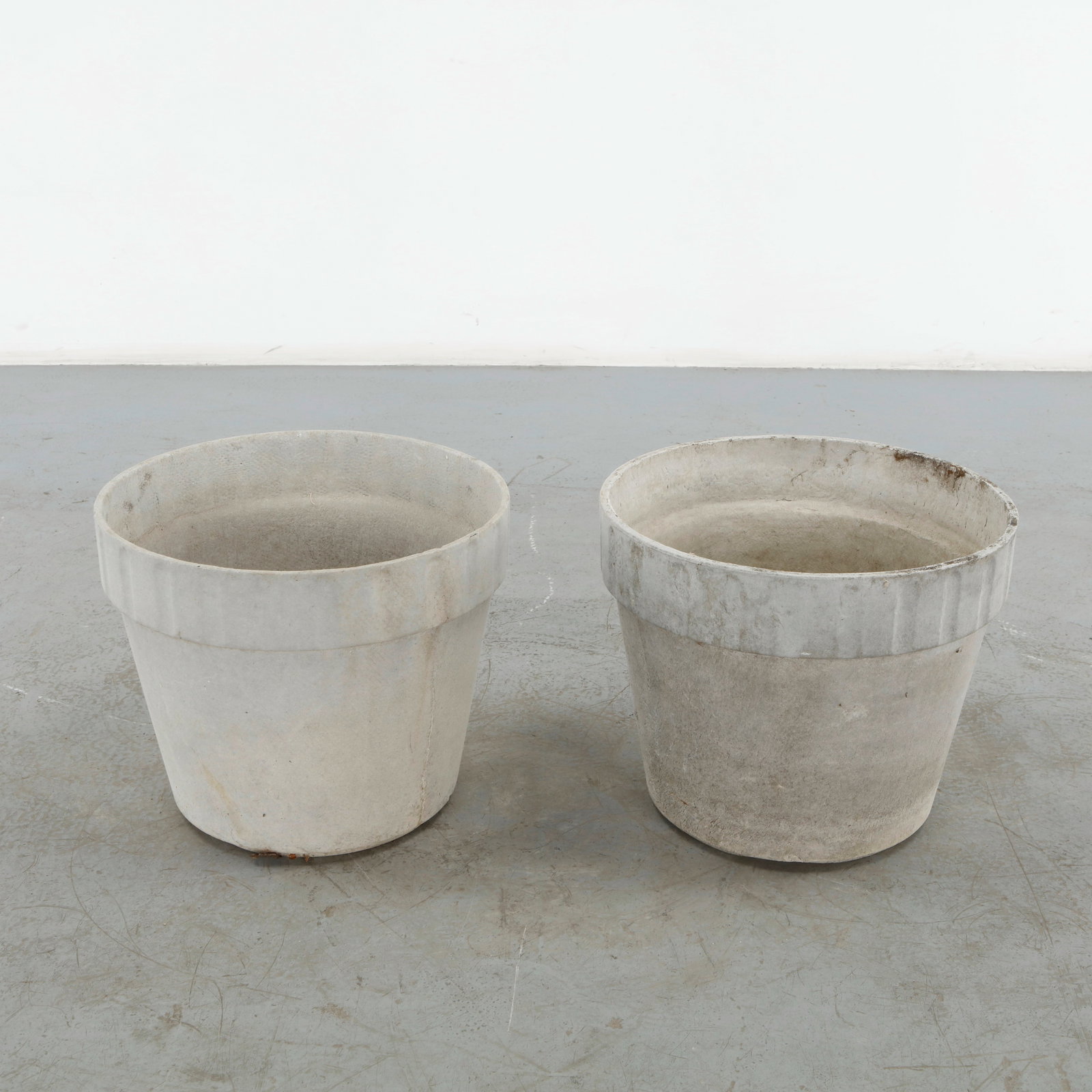 Willy Guhl, Pair of Round Planters, 1960s: Pair of substantial round planters in concrete, featuring softly tapering bodies and pronounced upper rims. Their restrained geometry is complemented by an authentic weathered surface developed throug