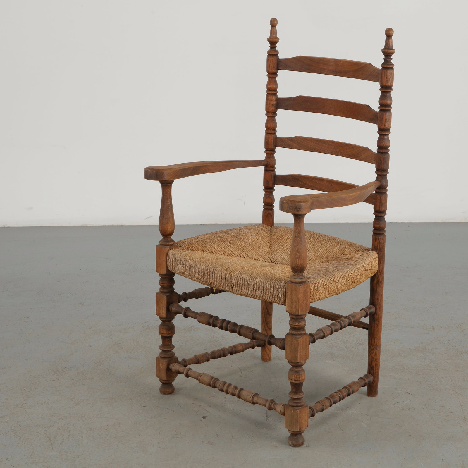 Woven Rope Armchair, 1960s: A distinctive 1960s armchair combining a richly turned solid wood frame with a handwoven rope seat. The elaborately articulated spindles, stretchers, and sculptural ladder back lend the piece a strong