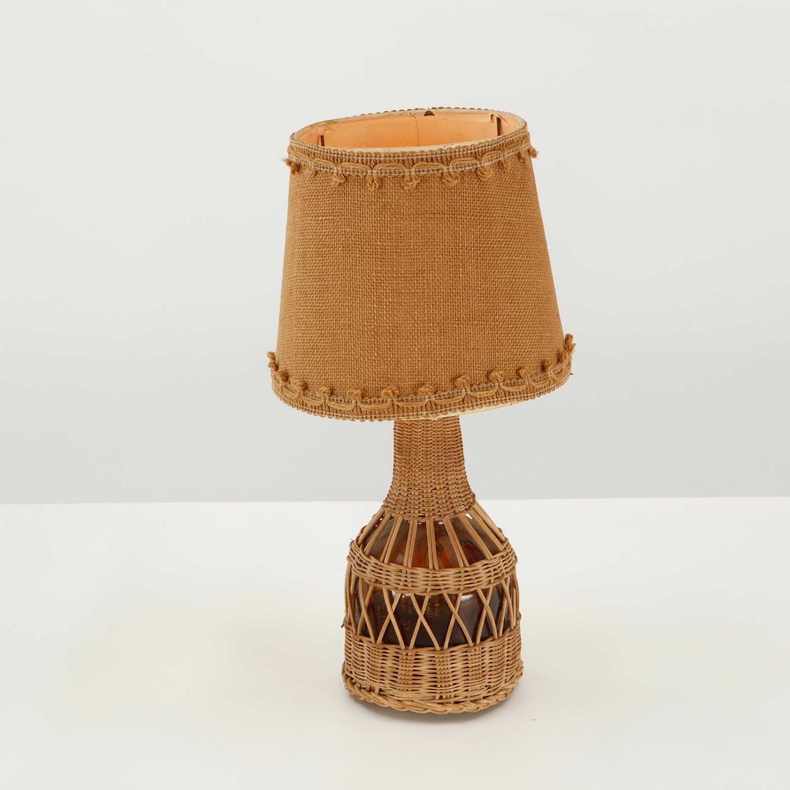 Louis Sognot, Woven Rattan Table Lamp, 1960s: Louis Sognot table lamp executed in natural rattan, featuring a finely woven tapered shade and sculptural woven base. The combination of organic materials and intricate handwork reflects the French mi