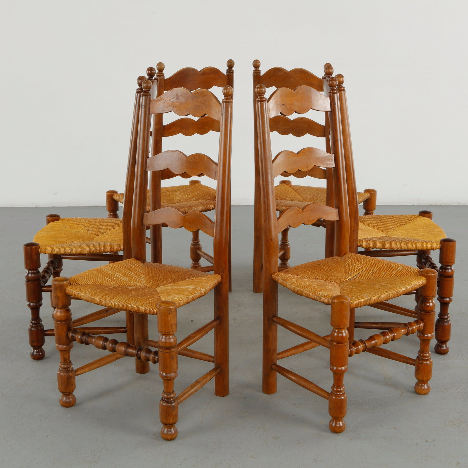 Set of Six Chairs in the Style of Charlotte Perriand, 1960s: A set of six wooden dining chairs in the style of Charlotte Perriand, distinguished by warm honey toned timber, woven rope seats and rhythmic scalloped ladder backs. The repeated organic forms and tur