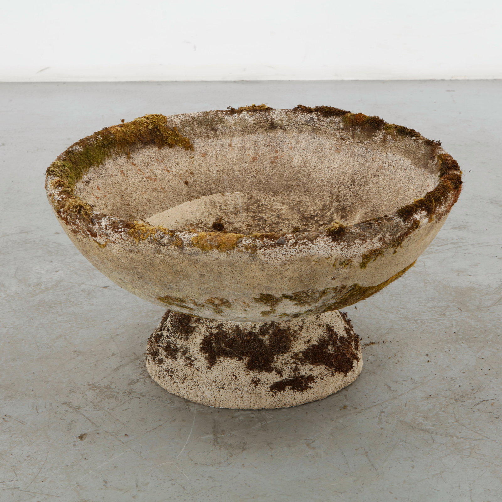 Cast Stone Planter on Stand, 1960s: A substantial cast stone planter of generous proportions, formed as a broad, shallow bowl on a low circular pedestal. Its heavily weathered surface and moss-covered patina accentuate the sculptural