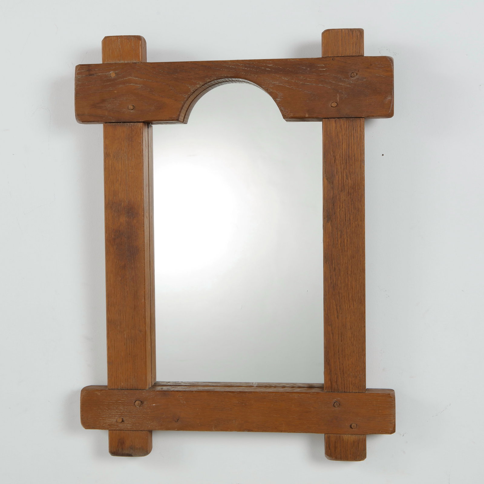 Rustic Oak Mirror, Arched Crest, Brutalist Style: A rustic mirror in solid oak, with a chunky post-and-lintel frame and an arched cut-out crest at the top. Visible peg joinery. Height: 28.5 in. Width: 21 in. Depth: 2 in.