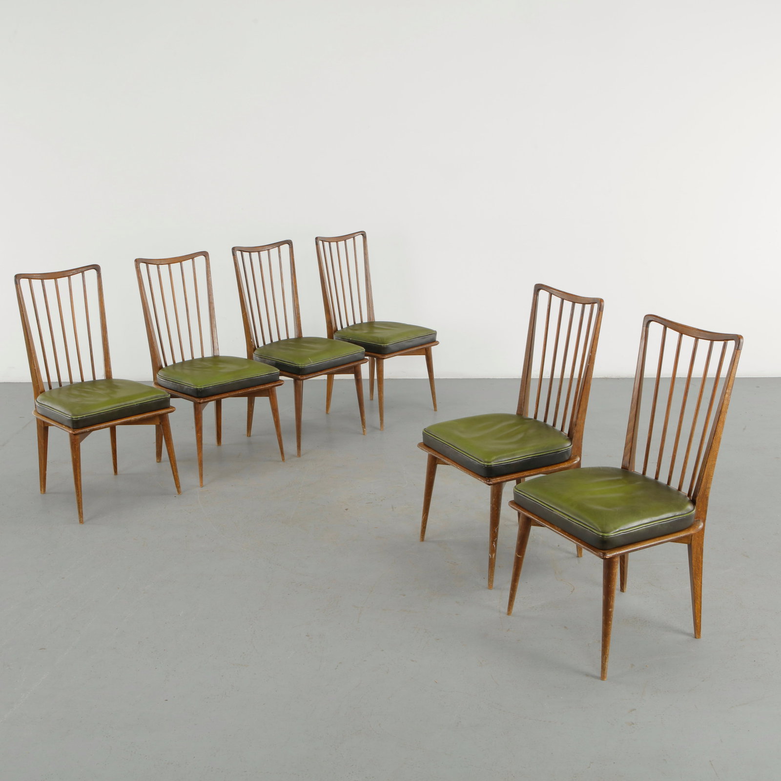 Charles Ramos, Set of Six Dining Chairs for Edition Castellaneta, 1960s: A set of six dining chairs by Charles Ramos for edition Castellaneta, featuring sculpted wooden frames, tall open backs with slender vertical spindles, and upholstered seats in olive green vinyl. Thei