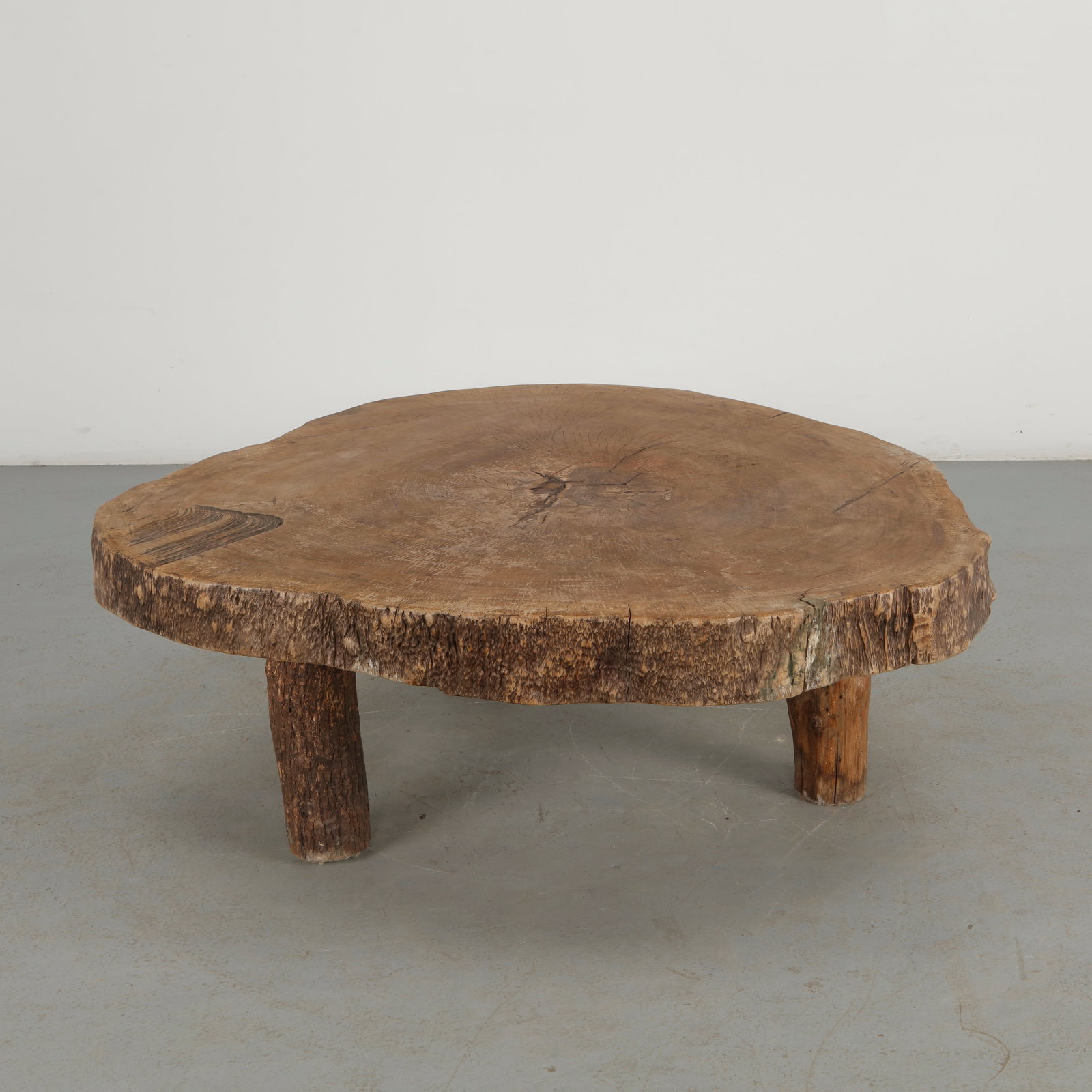 Monumental Live Edge Tree Trunk Table, 1960s: A monumental low table fashioned from a substantial section of tree trunk, retaining the natural edge and organic irregularities of the timber. The broad, hand-finished top celebrates the grain, crack