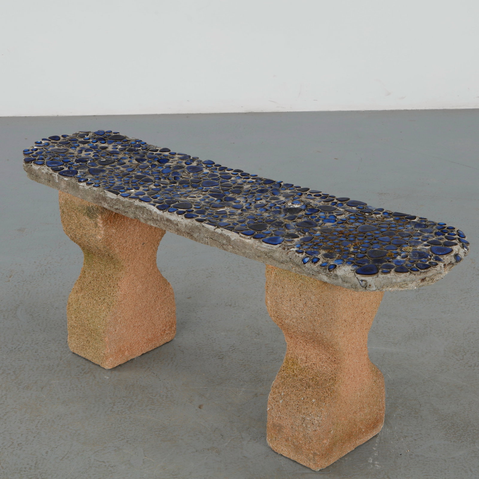 Blue Glass and Stone Bench, 1950s: A decorative outdoor bench featuring a mosaic seat composed of blue glass elements set within stone. The contrast between textured supports and luminous surface creates a playful yet structured compos