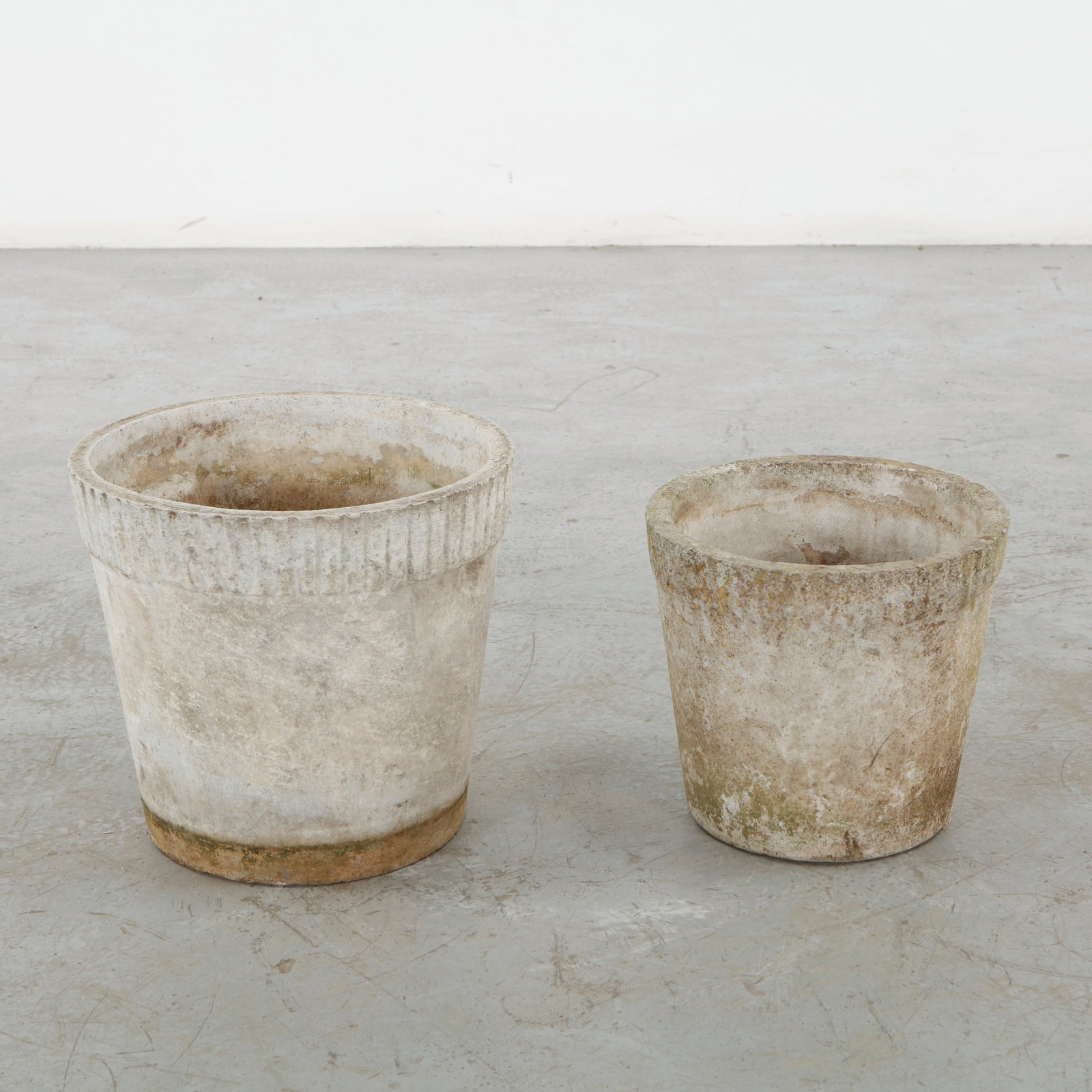 Willy Guhl, Pair of Round Planters, 1960s: A pair of cast concrete planters with broad circular profiles and gently tapered bodies, distinguished by their varied weathered surfaces. Their simple geometry exemplifies the enduring appeal of